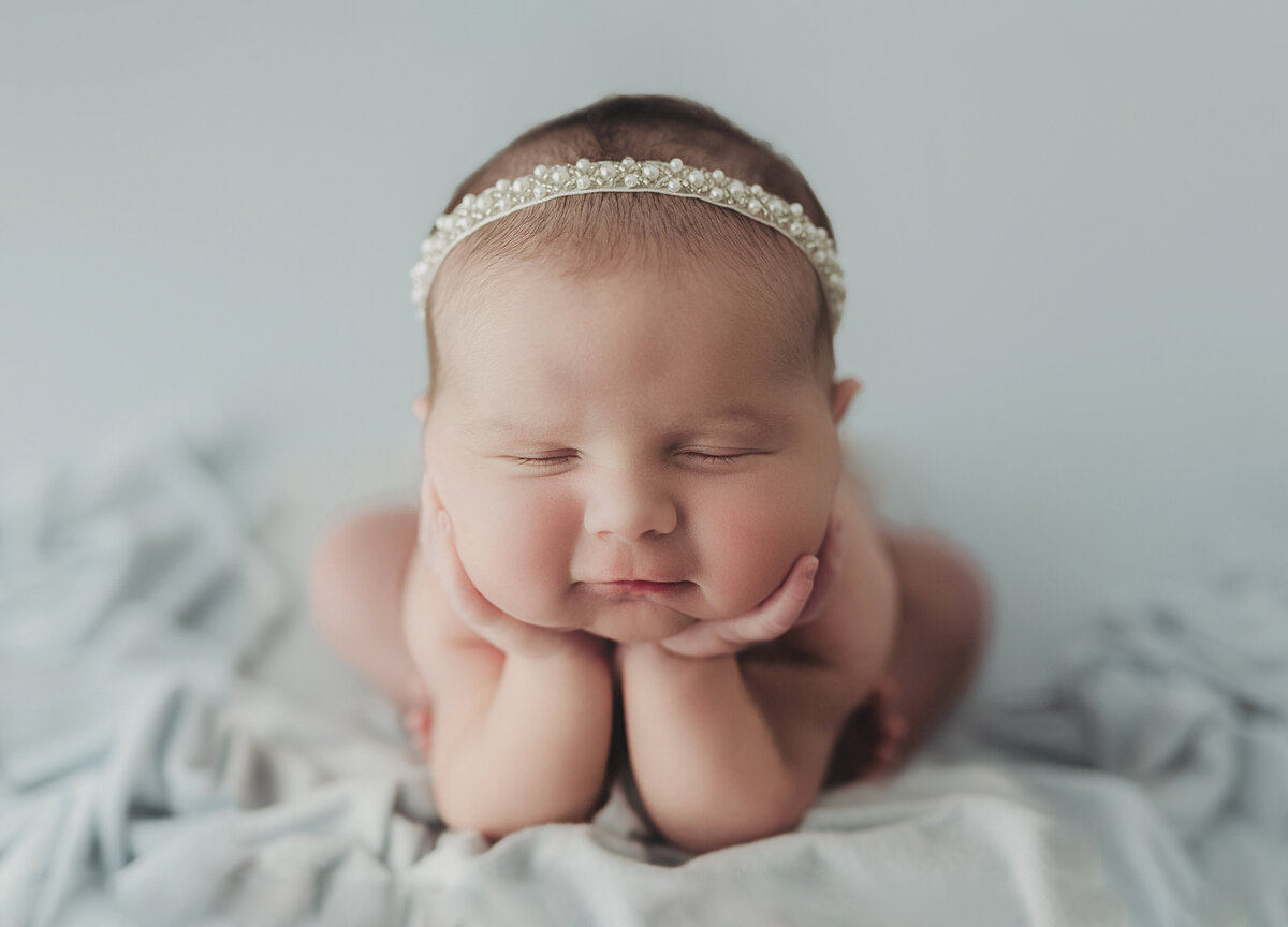 baby laying on blue backdrop in froggy pose