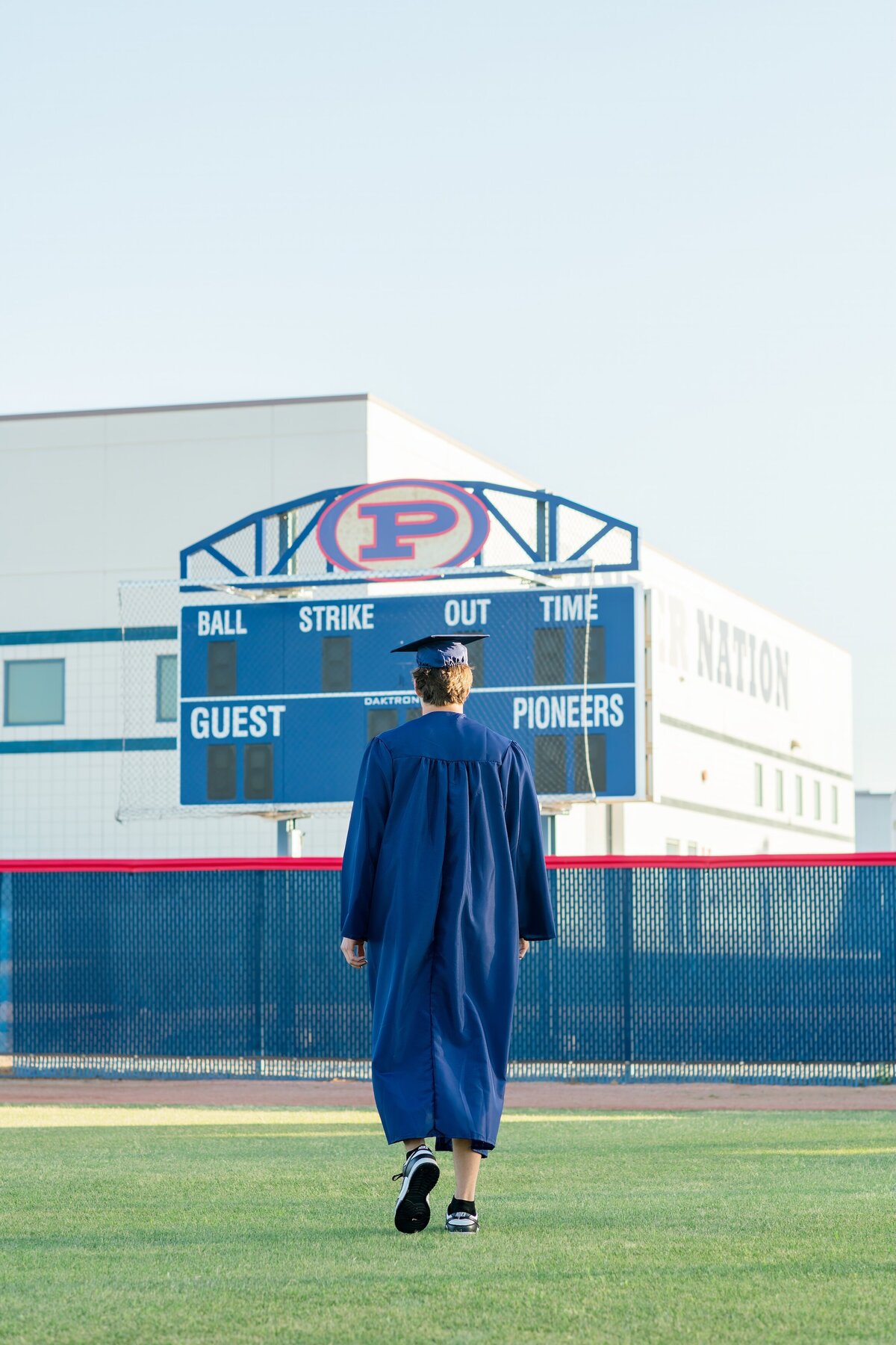 senior boy in the outfield of pinnical high school walking toward score board 