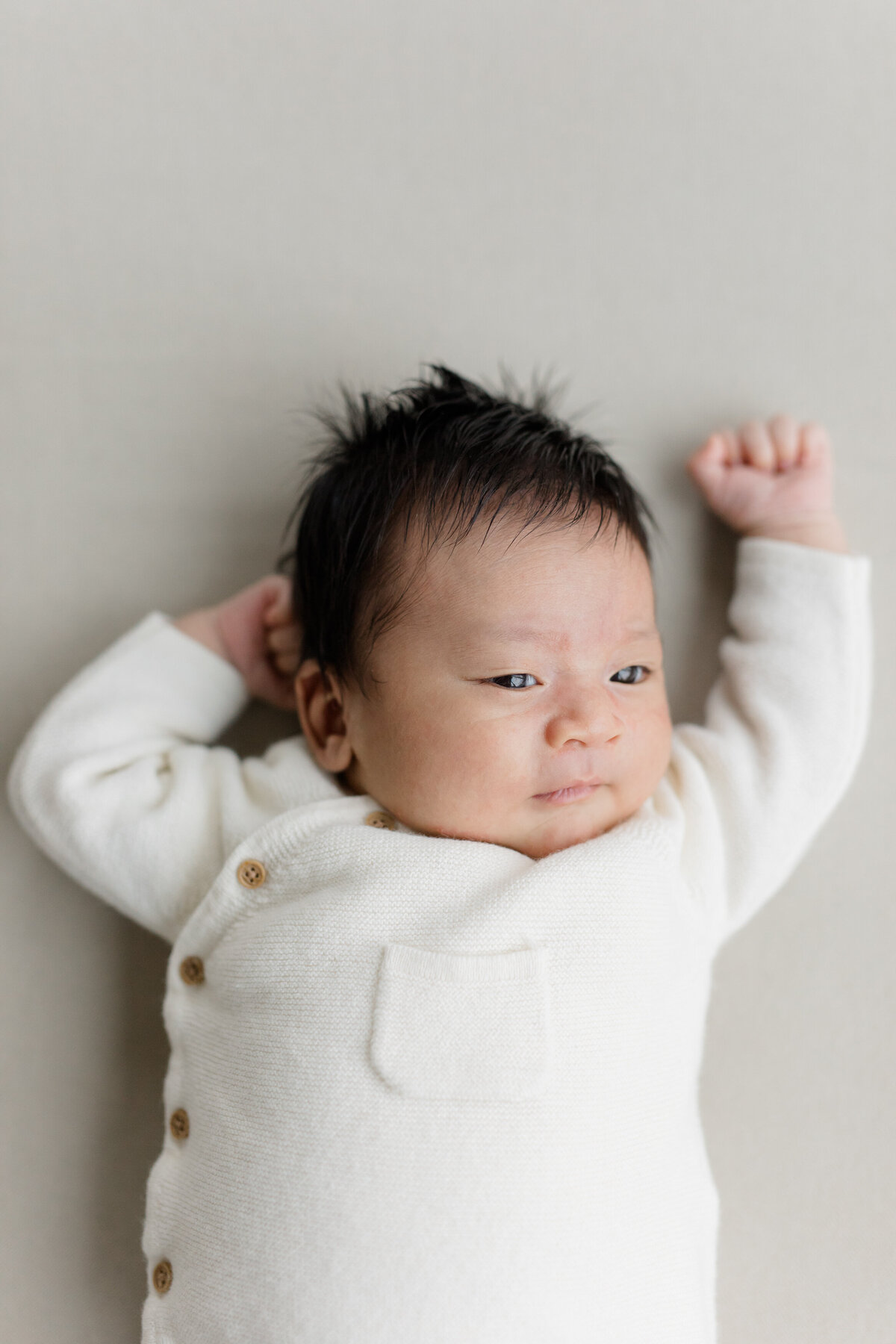baby boy on gray sheet looking off camera at Hamptons newborn photography session
