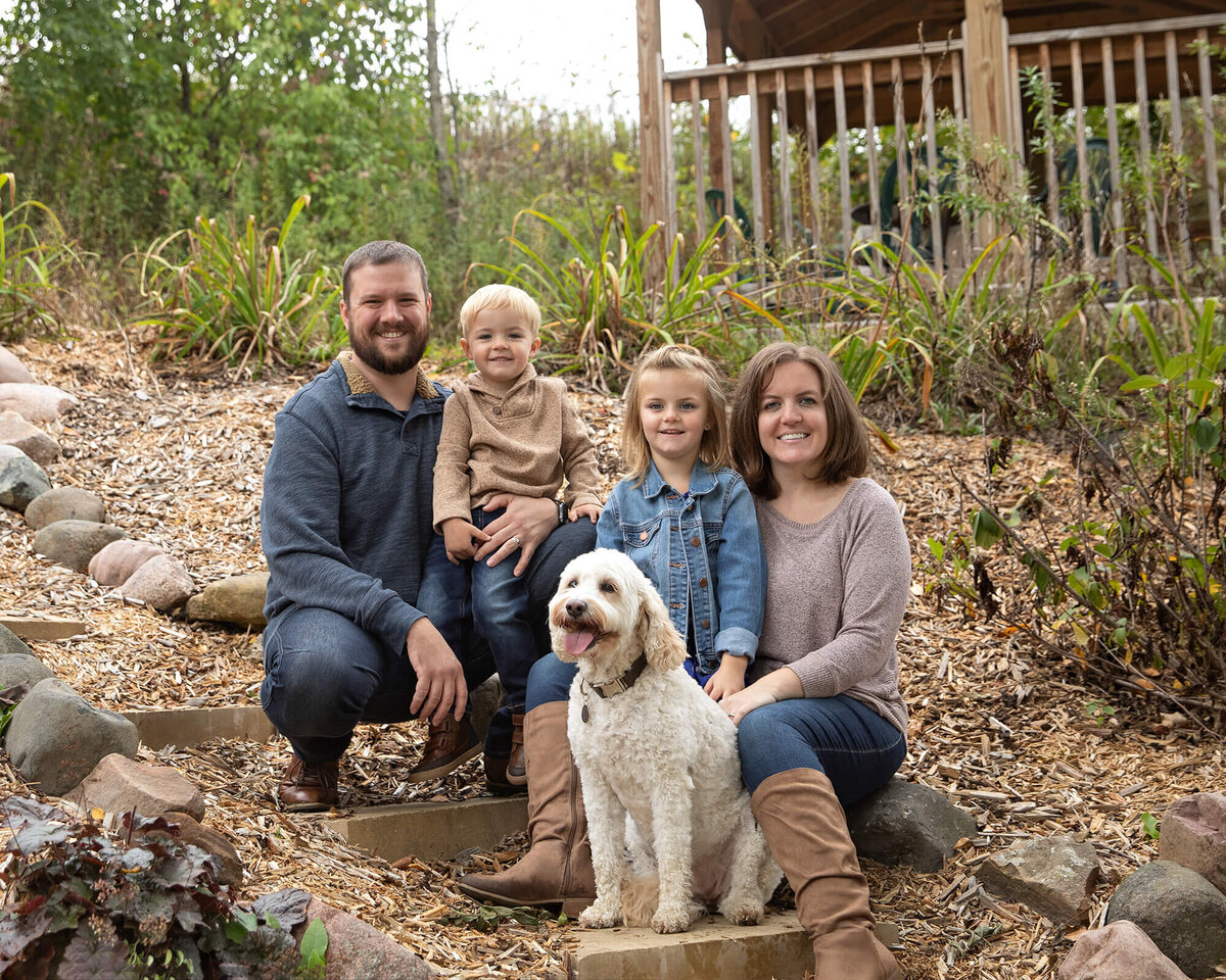 Dad, Mom, two children and dog sitting on different levels of stone steps.