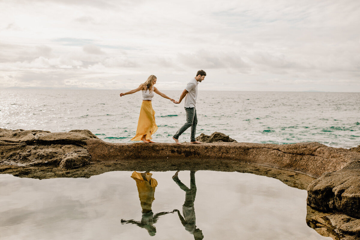 couple holding hands walking by the ocean