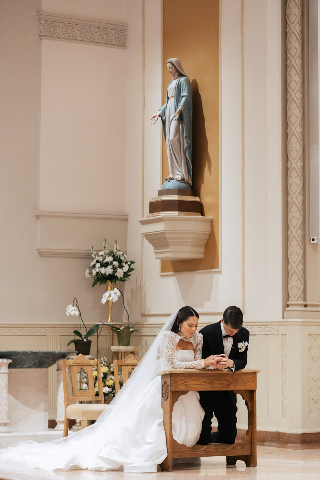 Ellie and Matt kneeling in prayer during their wedding ceremony at Holy Trinity Church.