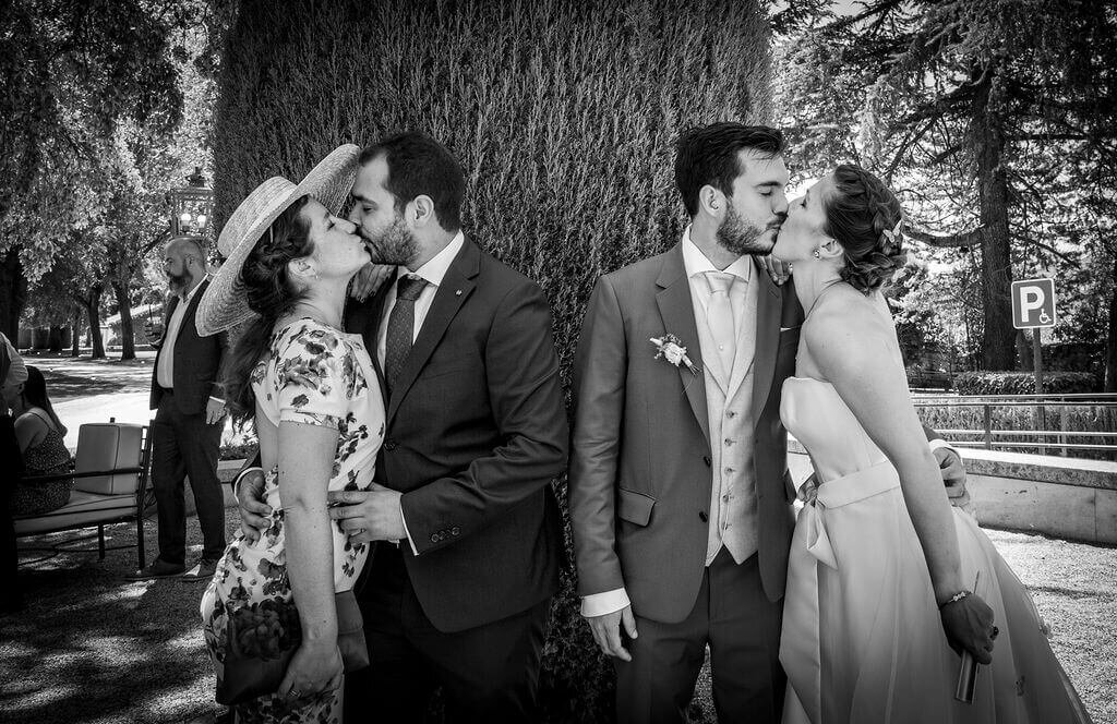 Alternative portrait of bride and groom with friends all kissing