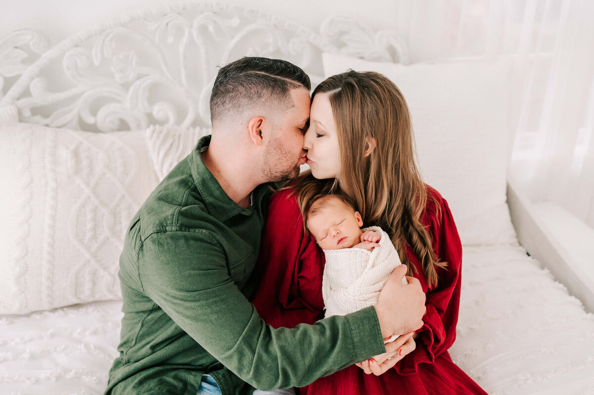 Springfield MO newborn photographer captures parents kissing holding sleeping baby boy