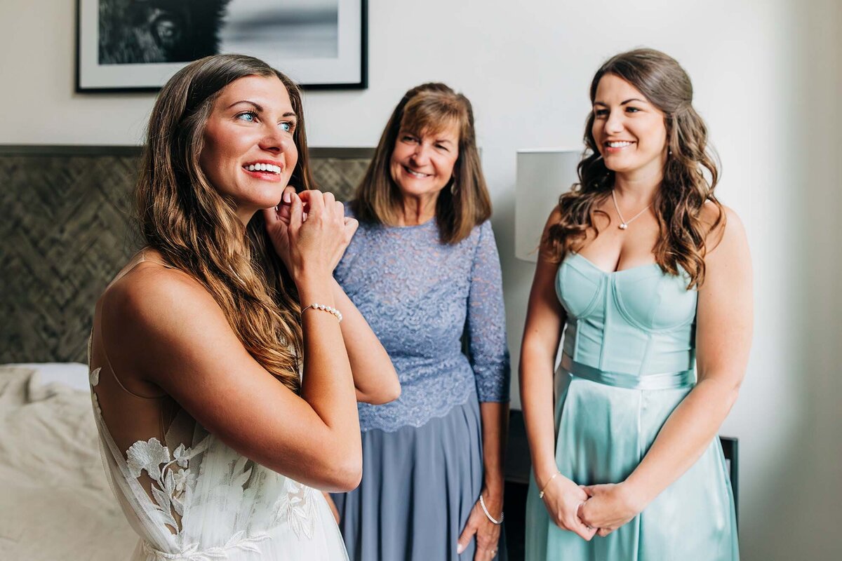 Bride putting on jewelry with mother and sister, Big Sky, Montana