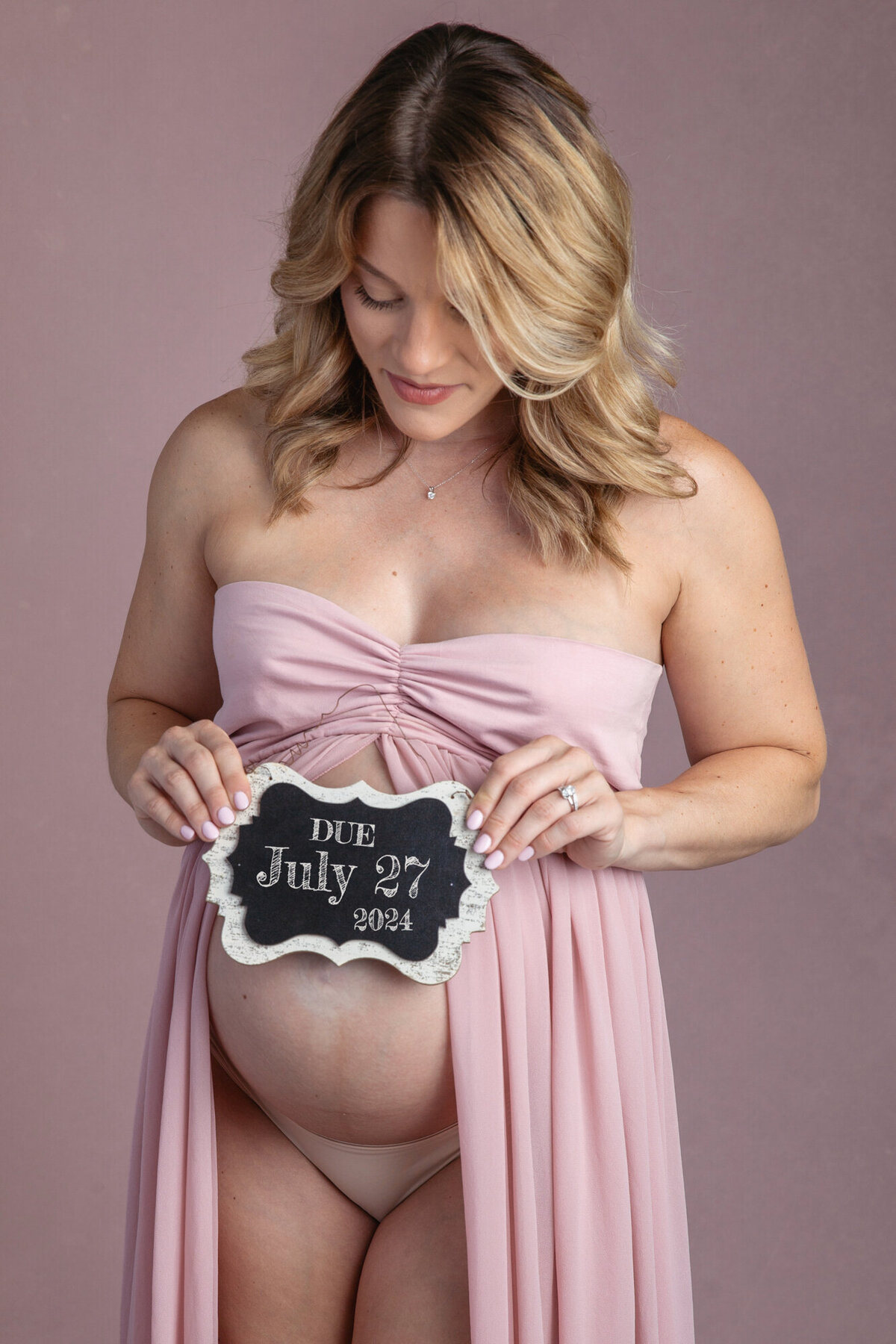 closeup image of a pregnant woman holding a chalk board near her belly