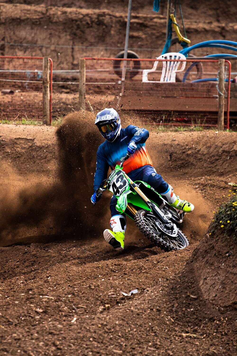 Motor cross racer takes corner at speed kicking up dirt