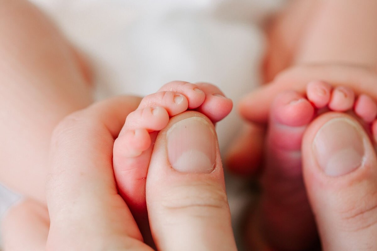 Mom holds newborn baby's toes.