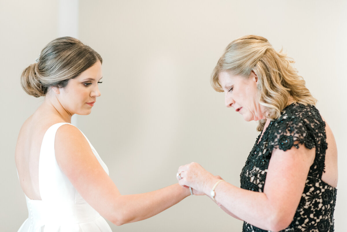 mother of the bride helping bride with her bracelet