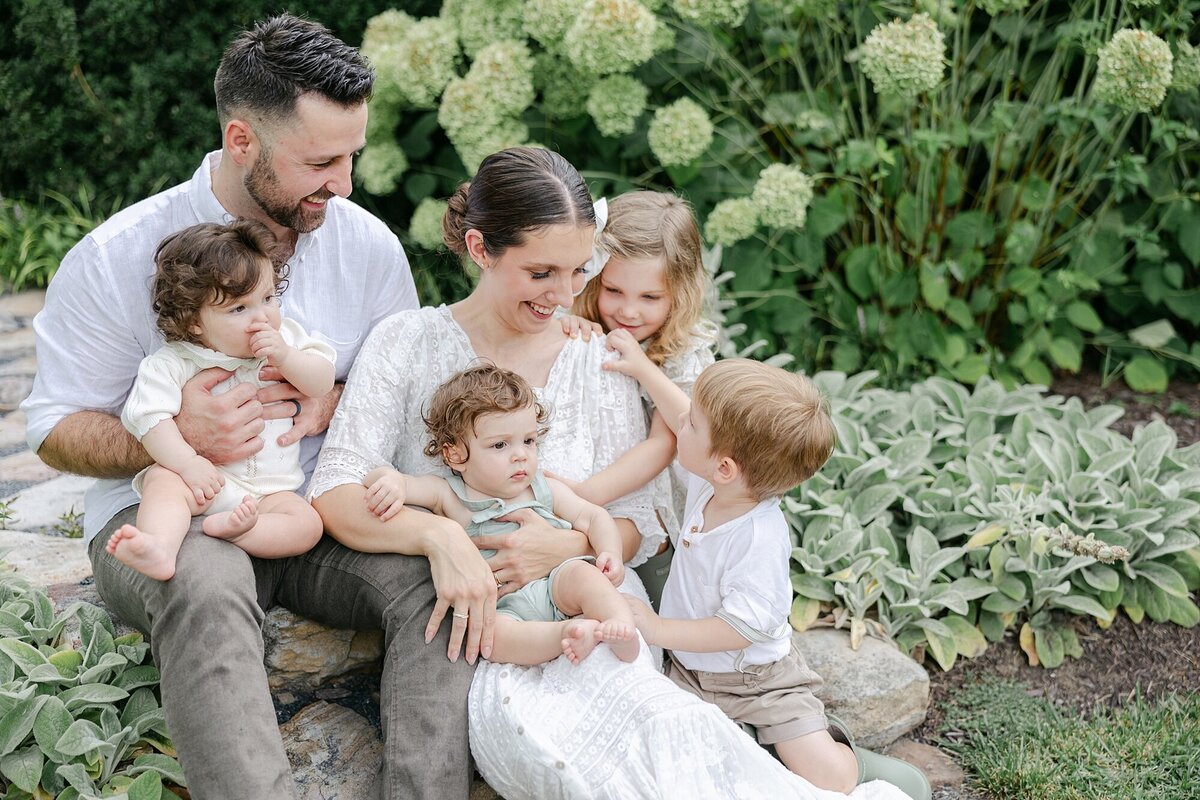 large family sitting on steps with hydrangeas in background