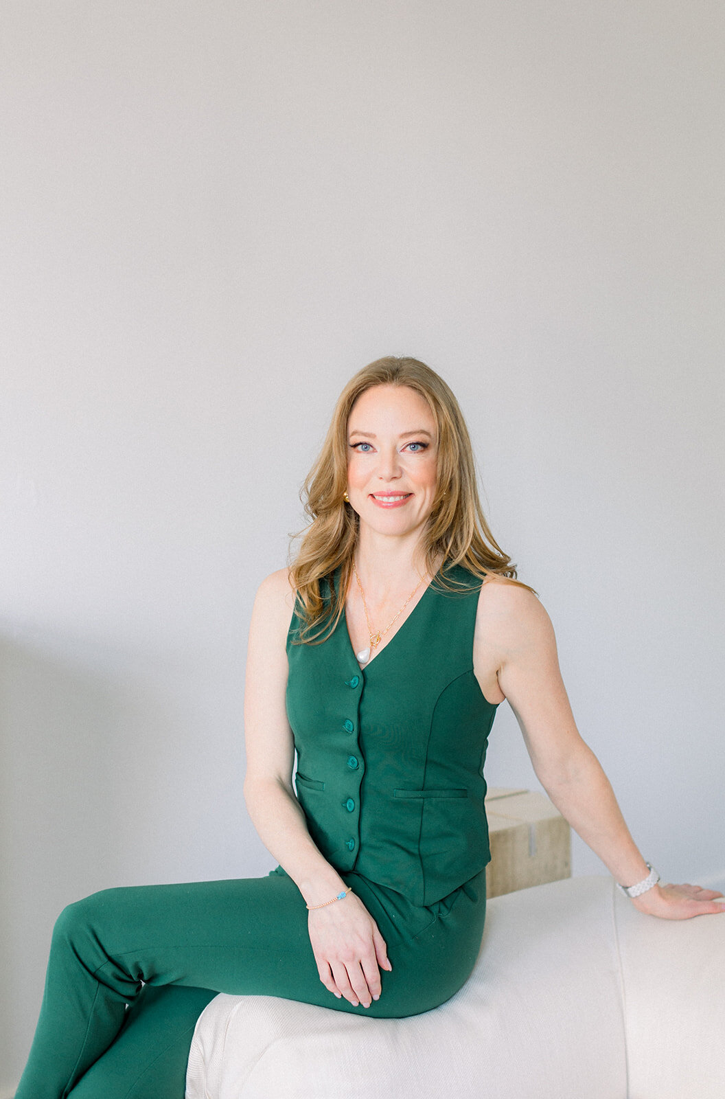 Branding headshot of Calgary business woman with red hair in a greeen vest and pants