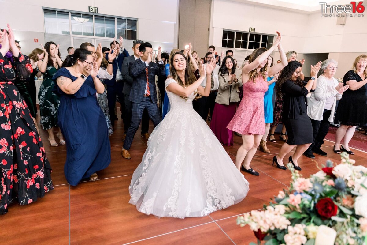 Bride leads wedding guests in a line dance during her wedding reception
