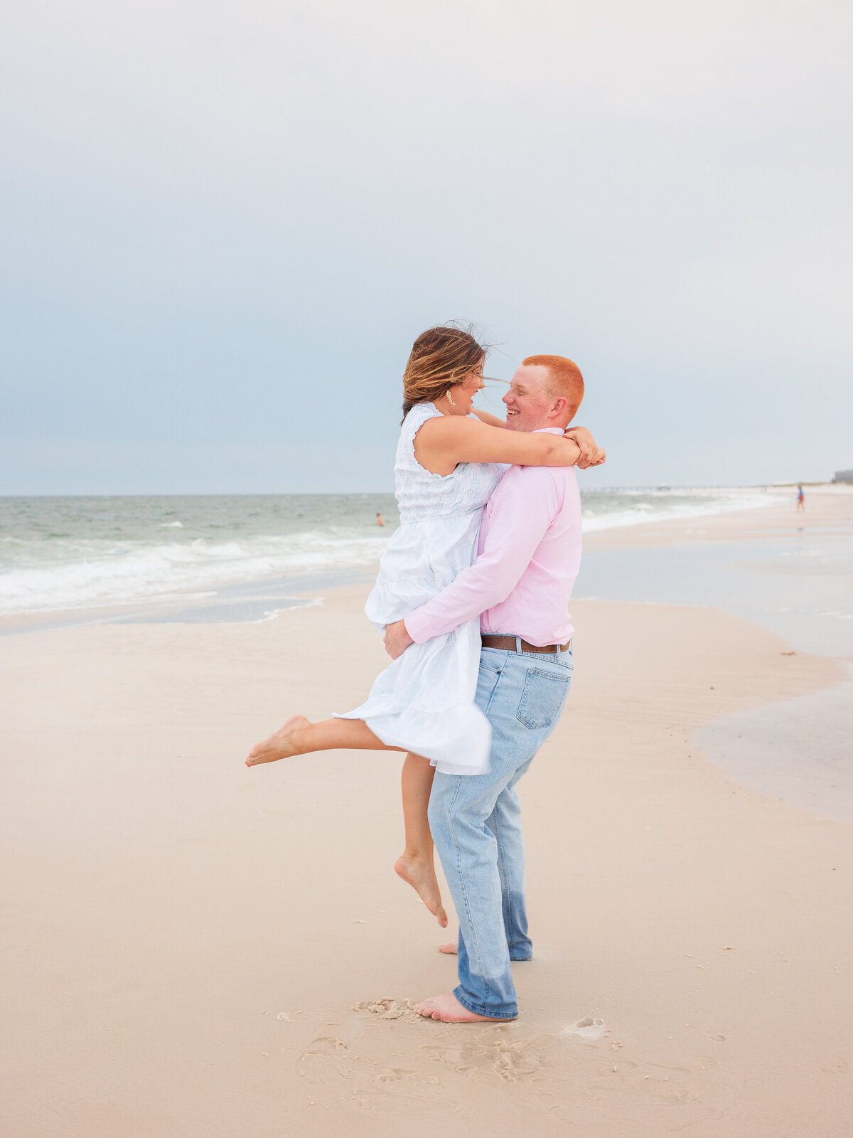 New couple spinning around on the sand with blue sky before sunset
