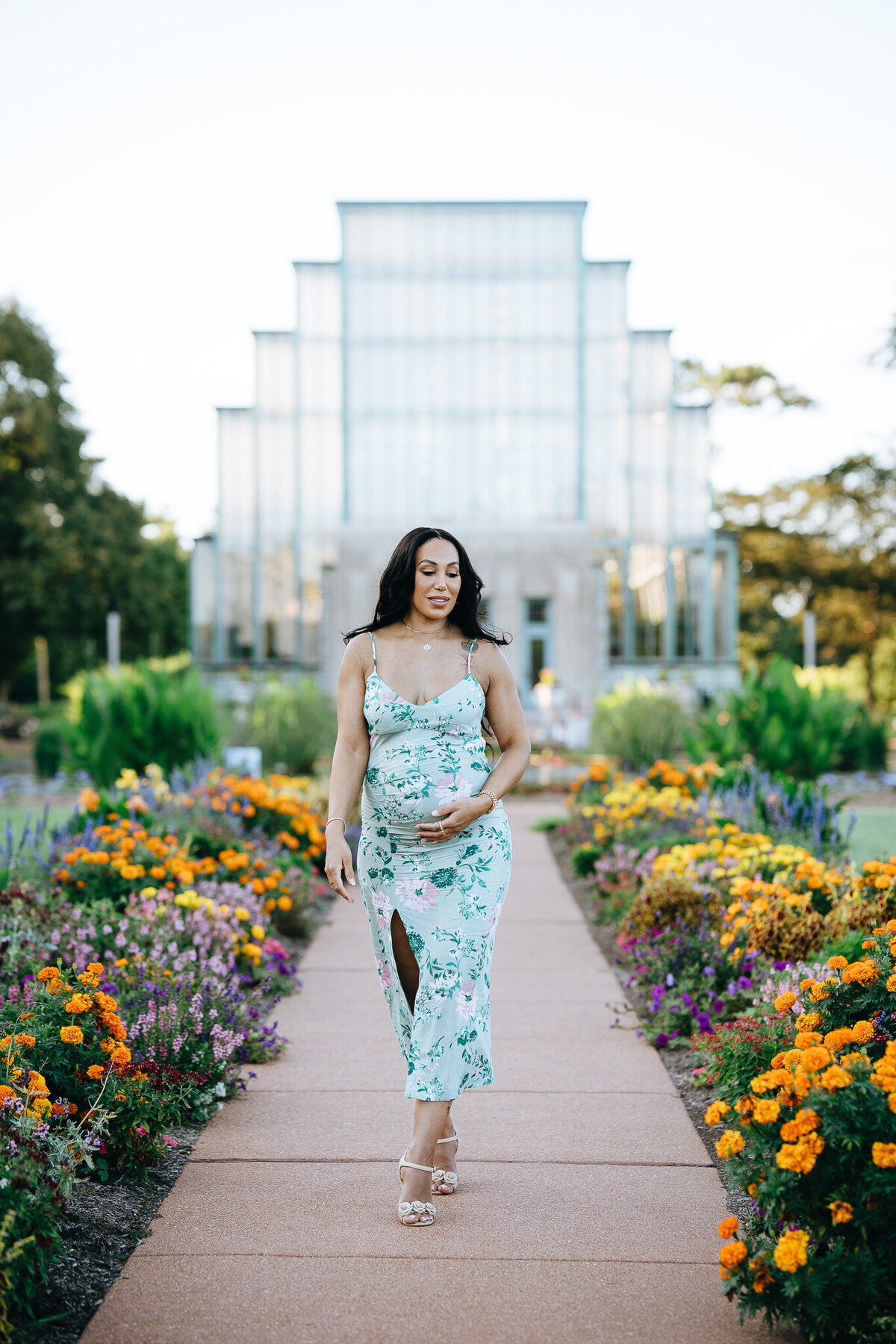 photo of pregnant woman walking by a row of flowers in front of the jewel box