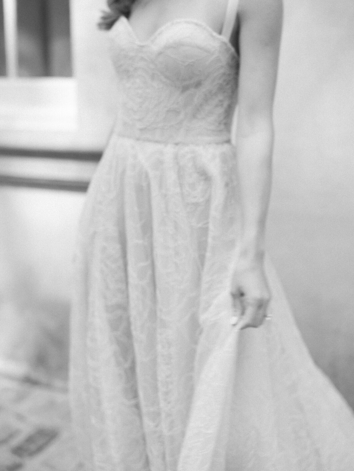 Black and White close up photo of bride's hand swaying dress.
