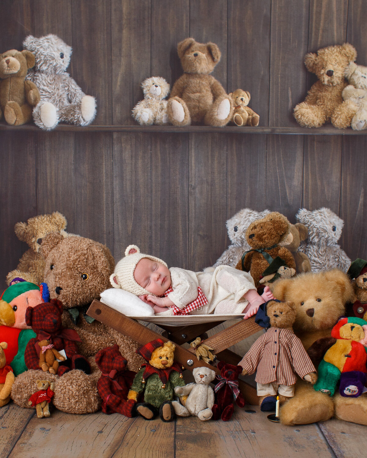 Newborn dressed in a knitted baby bear outfit laying on a bed with a bunch of teddy  bears.