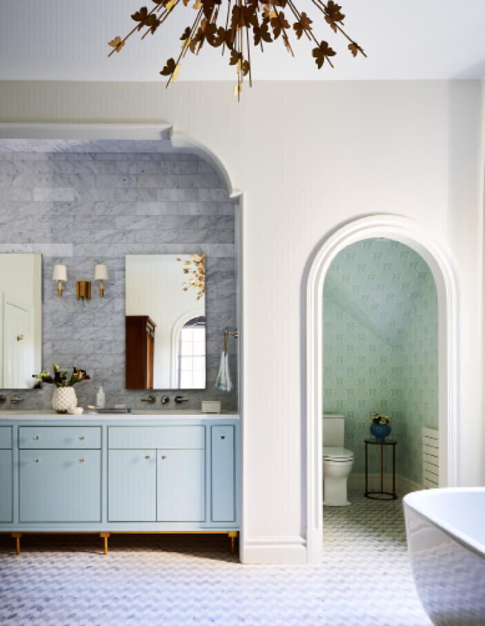Interior architectural design in Milton by a Boston decorator features a blue vanity and a water closet with Galbraith & Paul wallpaper for a timeless look.