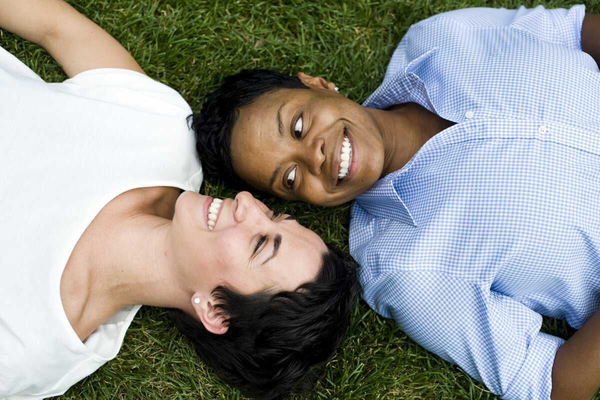 A couple laying on the ground head to head facing different directions 