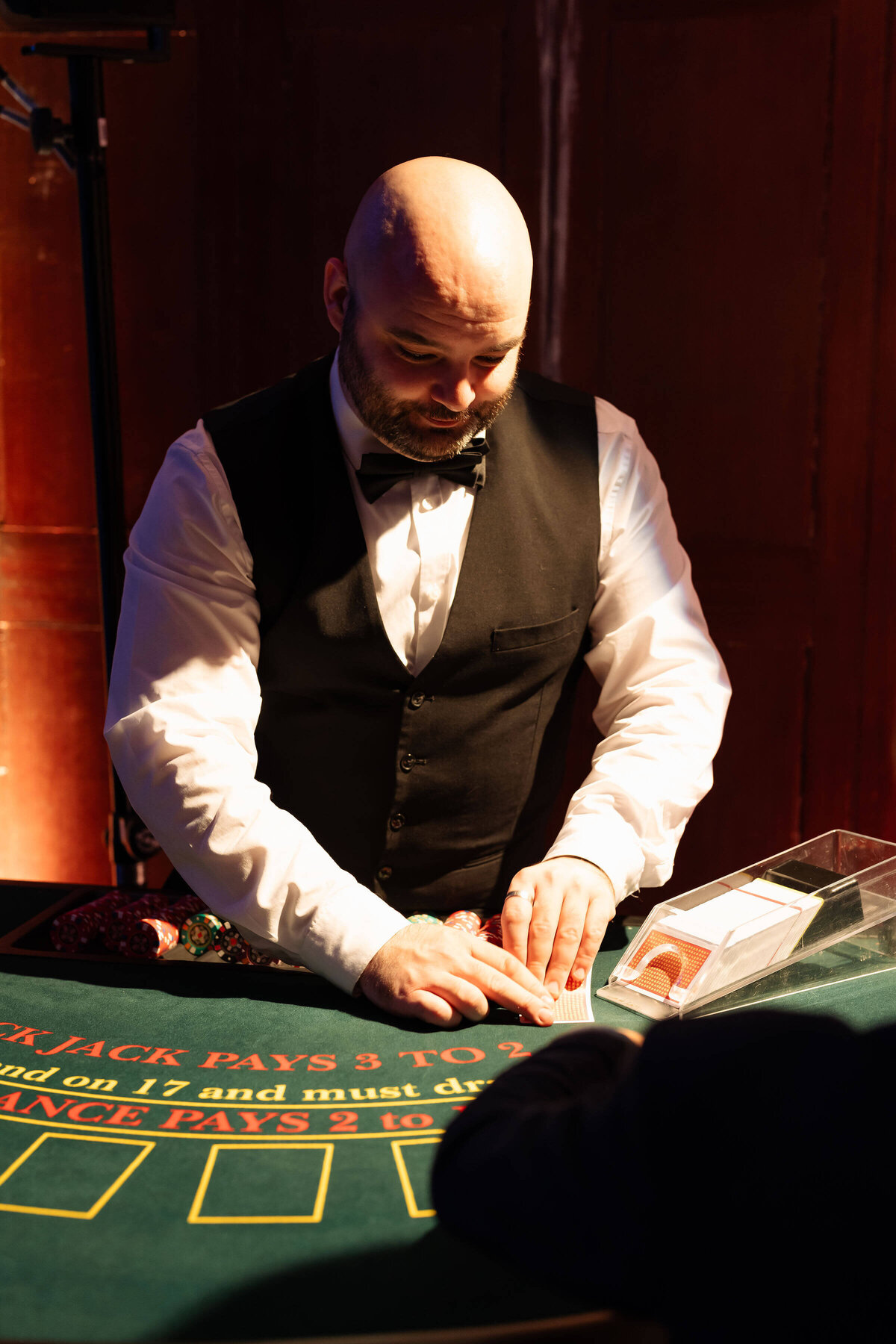 a croupier at a blackjack table laying out cards for a birthday party casino night in avington park