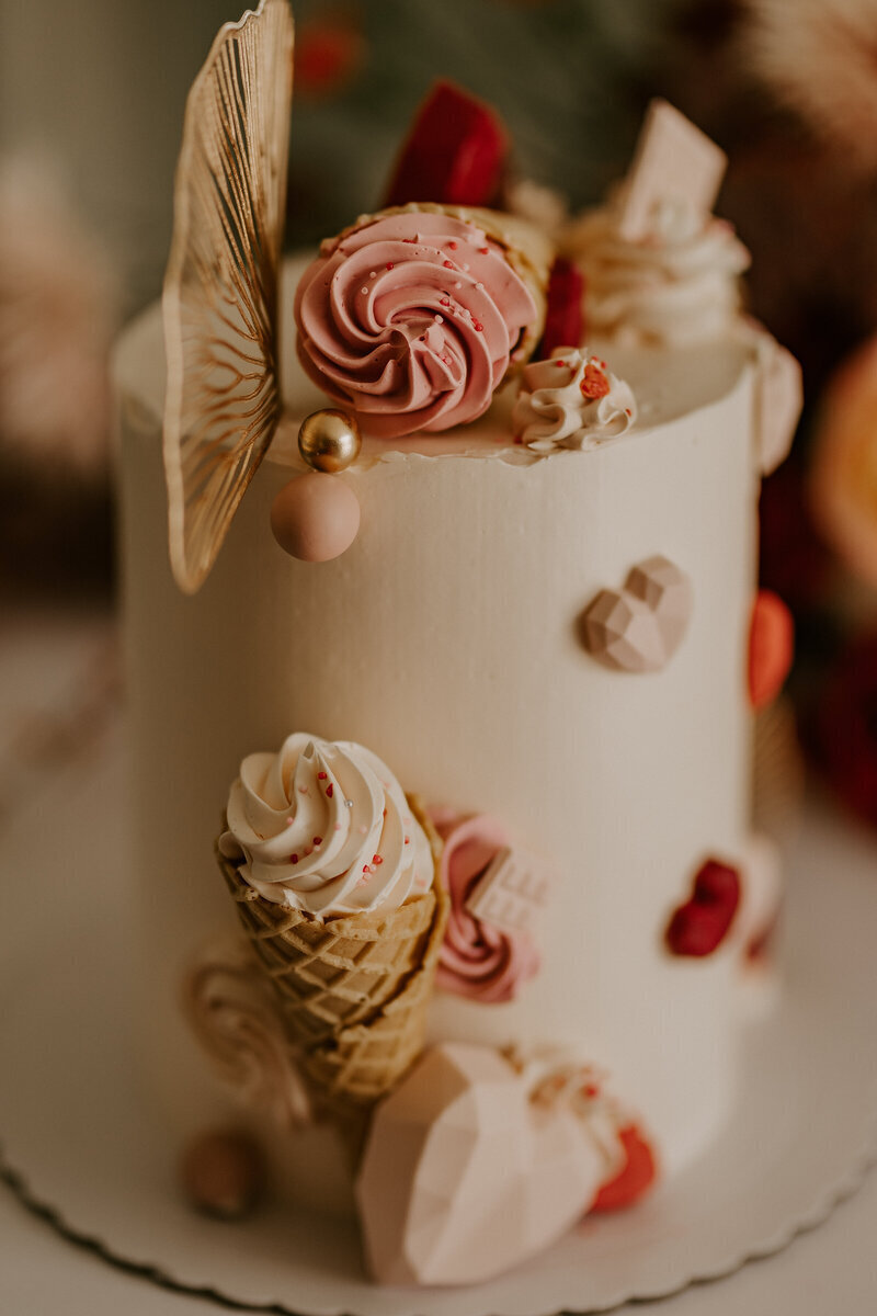 Wedding cake blanc et minimaliste agrémenté de cônes de glace rose et blanc et de petits coeurs. Photo prise par Laura, photographe professionnelle en Vendée.