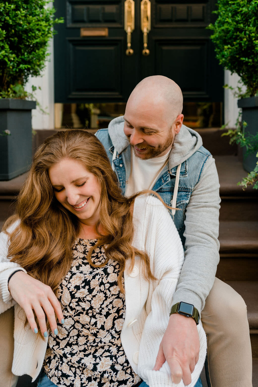 man smiling down at woman as they sit in front of each other on a small staircase