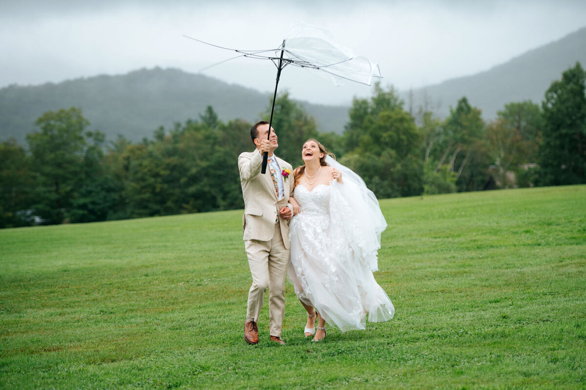 couple walking with umbrella inside out at mountain top inn and resort in chittenden vermont
