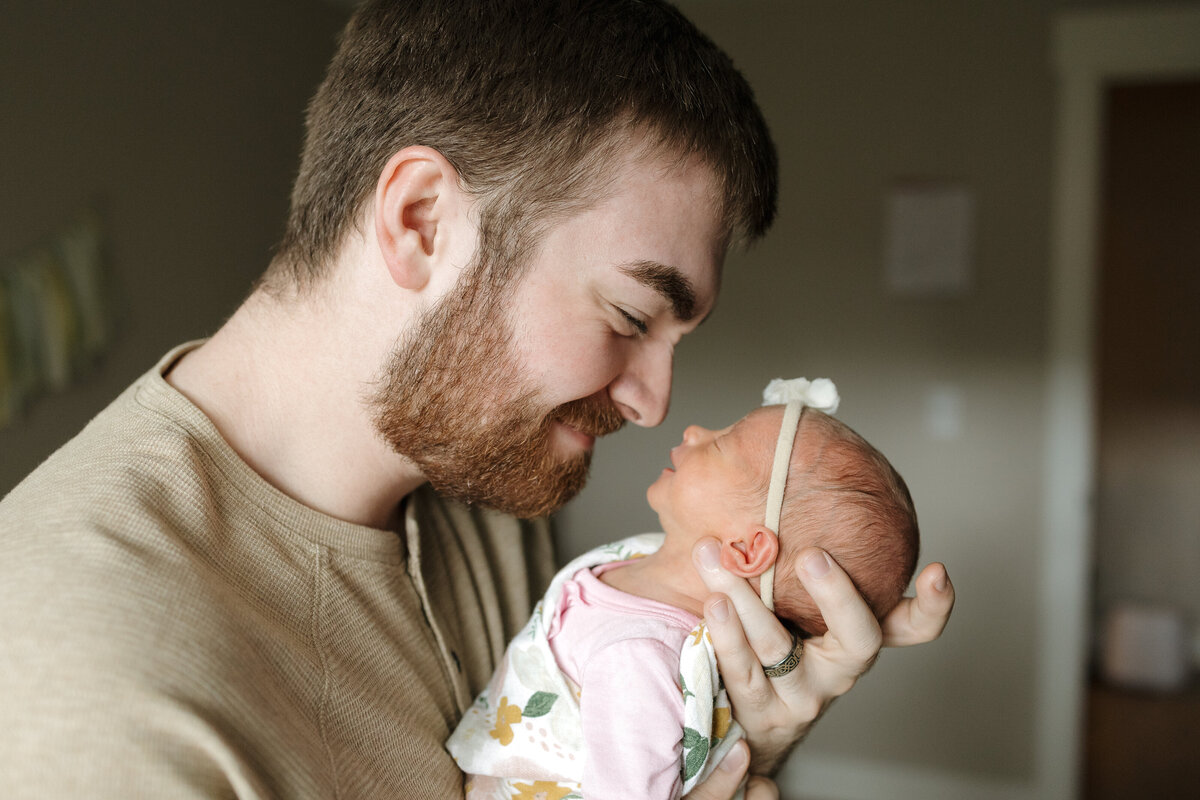 Longmont CO dad looking down at newborn smiling while newborn smiles up at dad