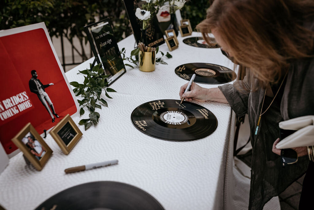 Guest book table at a spring wedding at the Palm Event Center in Pleasanton, CA, featuring a unique guest book idea where guests sign vinyl records.