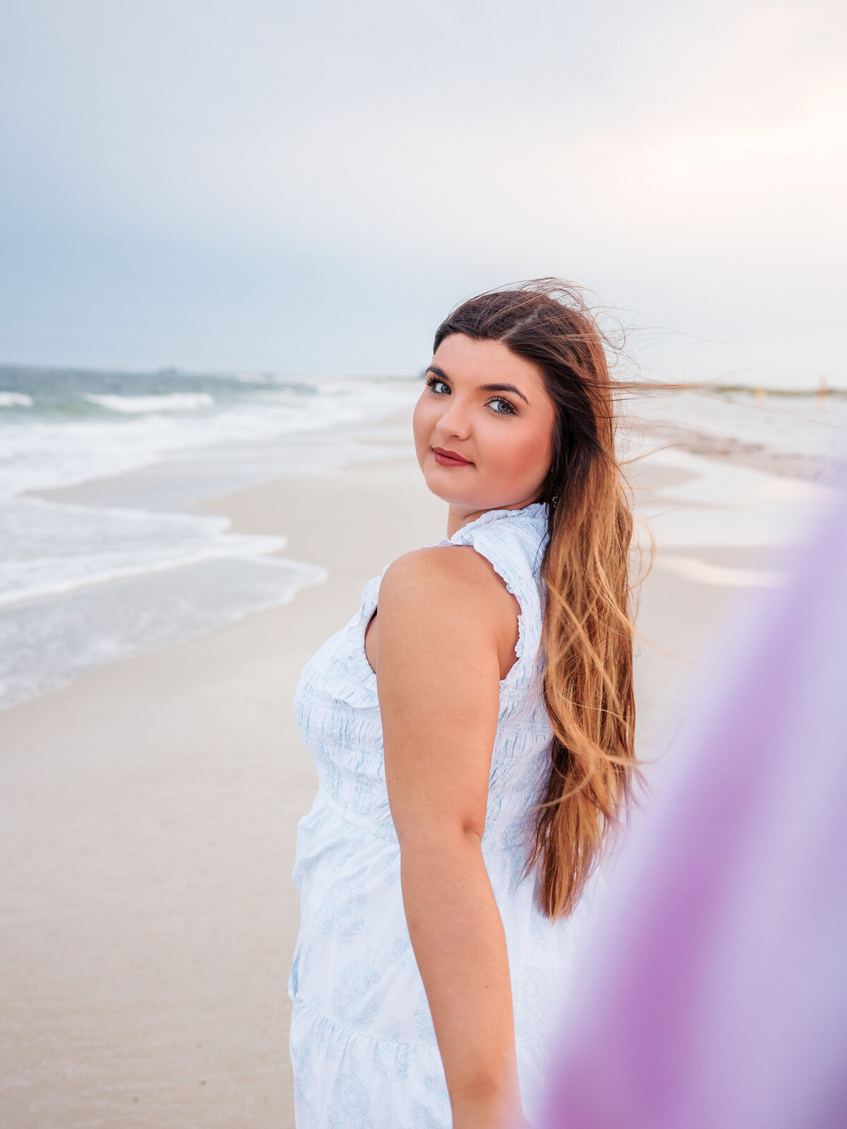 Beautiful photo of girl looking over shoulder as she leads guy along the shoreline with waves crashing 
