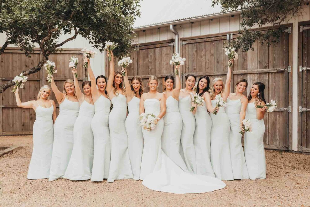 bridal party throws their hands in air for bridal photos.
