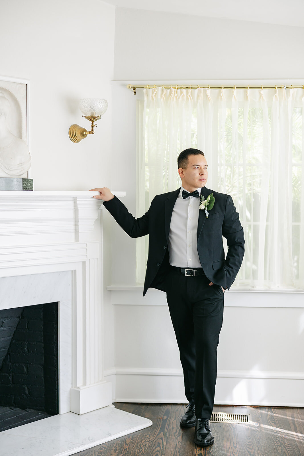 Groom by fire place taking his solo pictures in a tux at The Capen House in Winter Park Florida