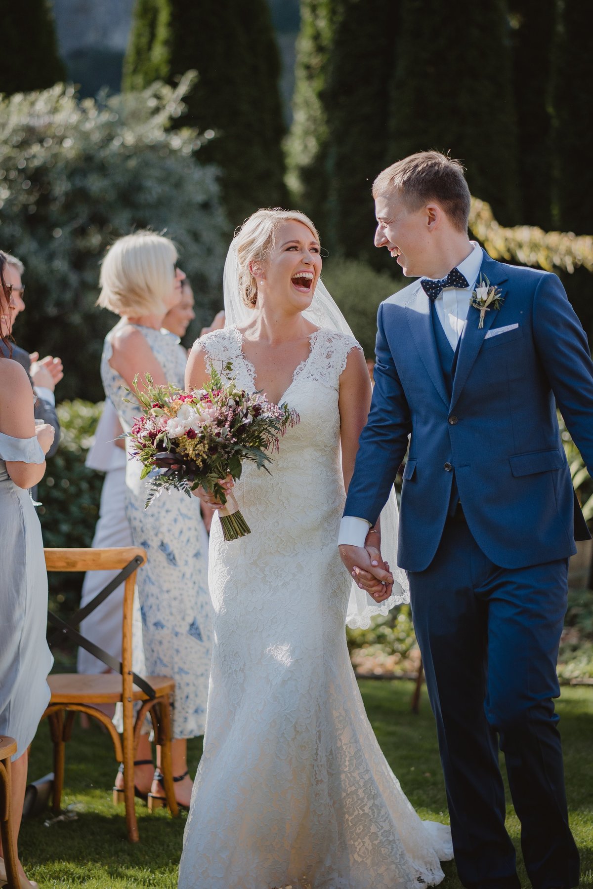 bride and groom laughing as the walk holding hands down the aisle