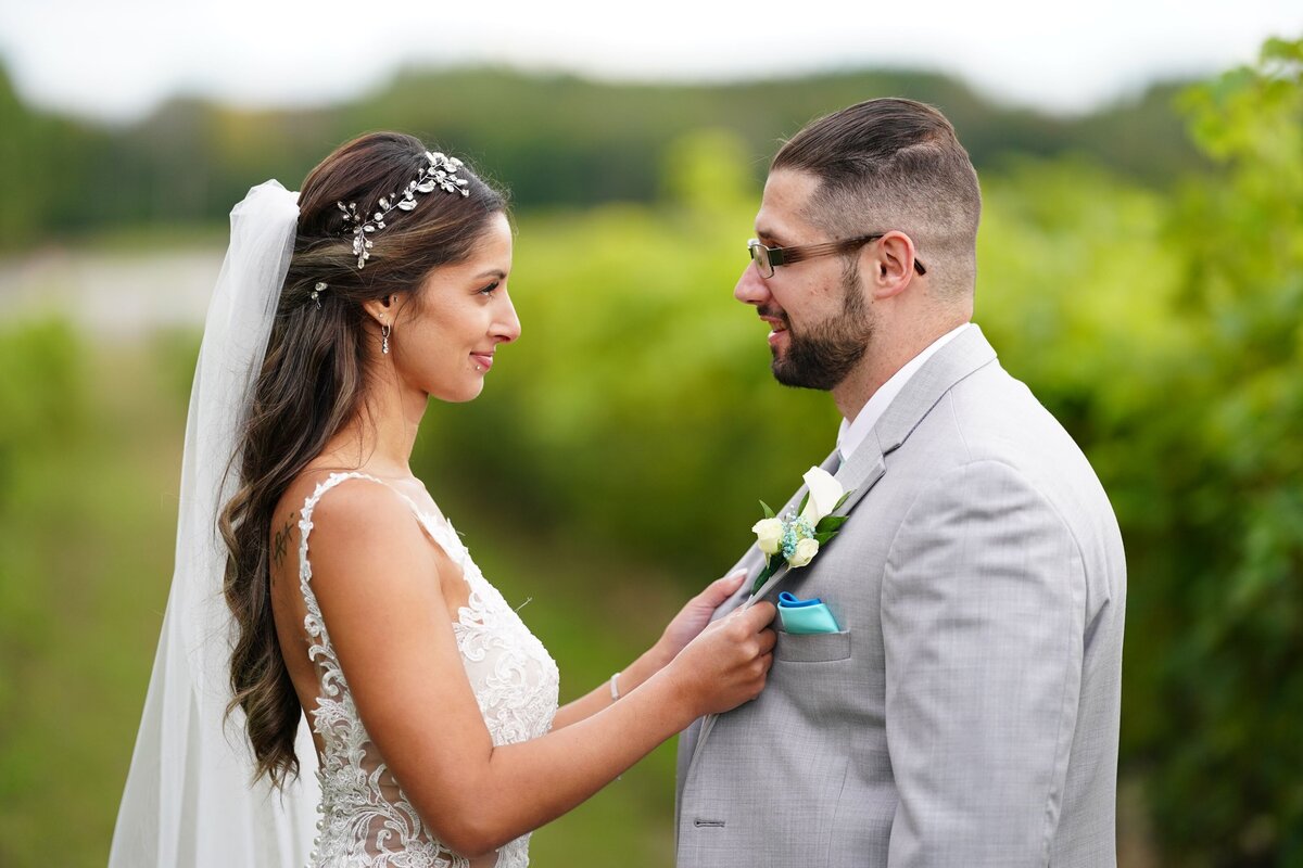 The bride lovingly holds the groom by his lapels, creating an intimate and affectionate moment. The close-up shot highlights the couple’s connection and the bride’s delicate touch.