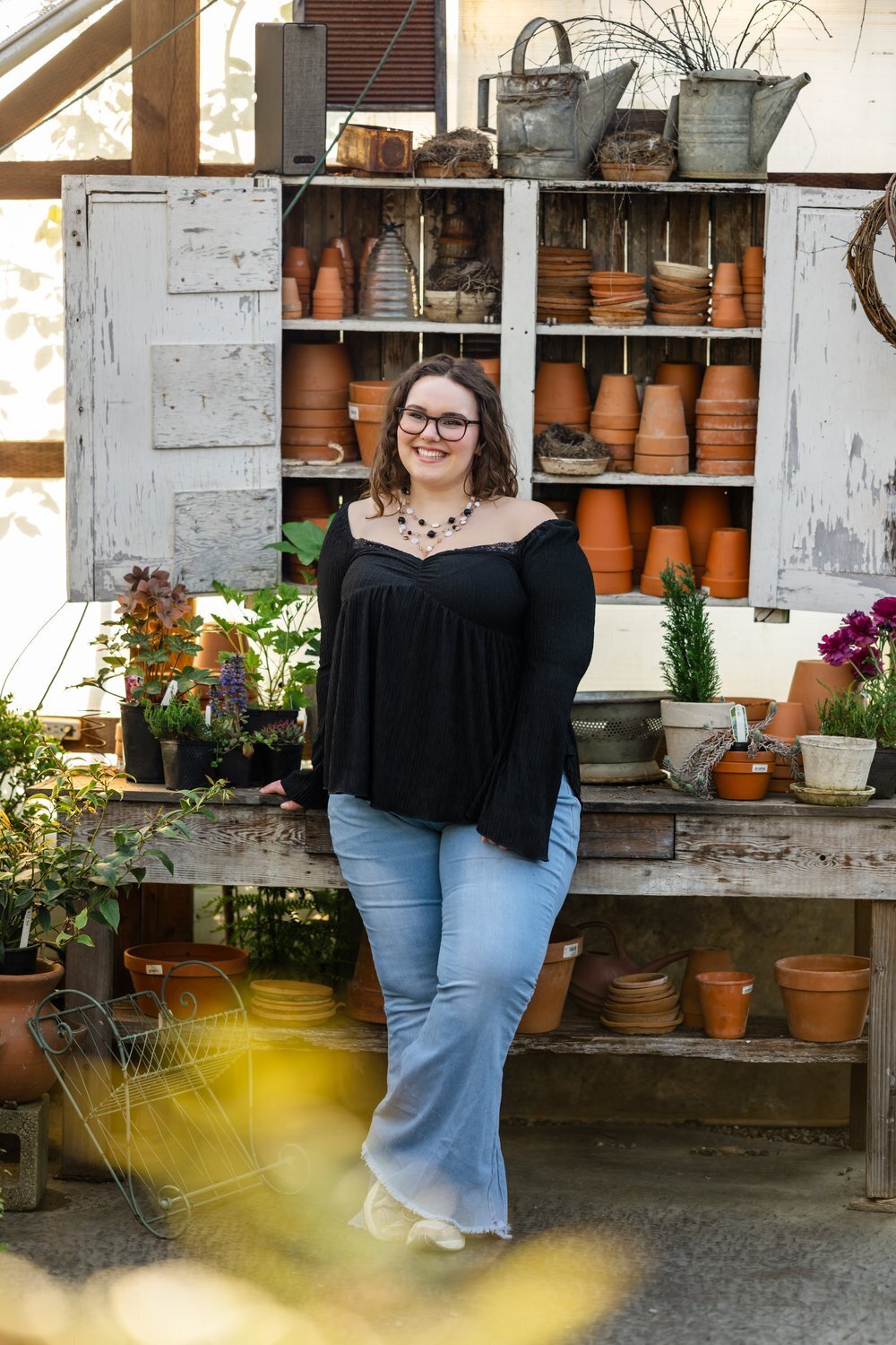 redmond high school senior poses inside nursery in jeans and black top
