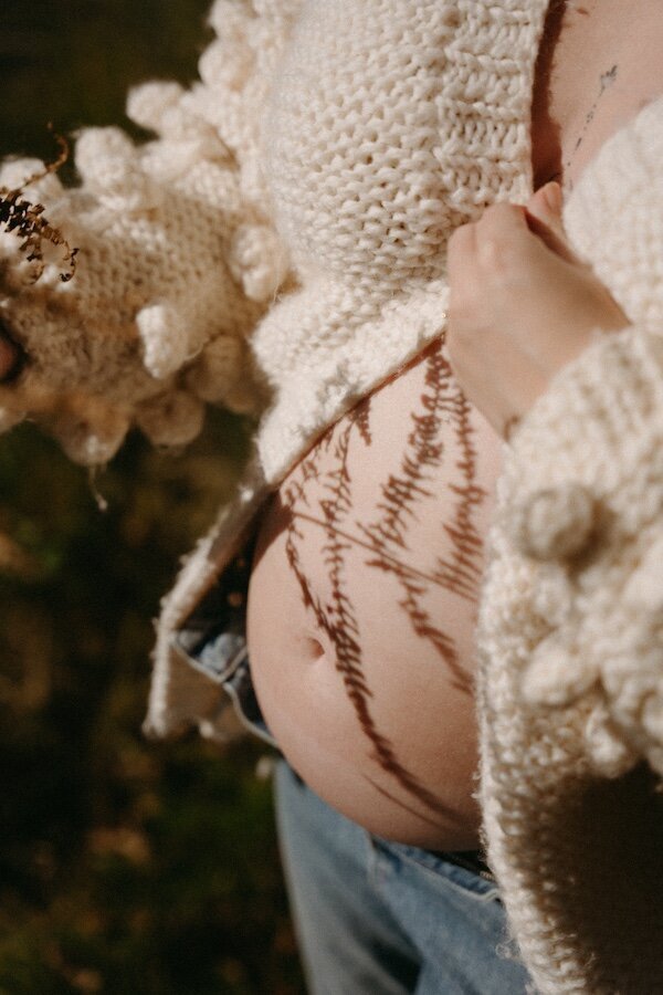 Future maman en pleine nature. Ombre d'un feuillage sur son ventre rebondi et apparent.Photographe Kamescop, séance grossesse en Bretagne.