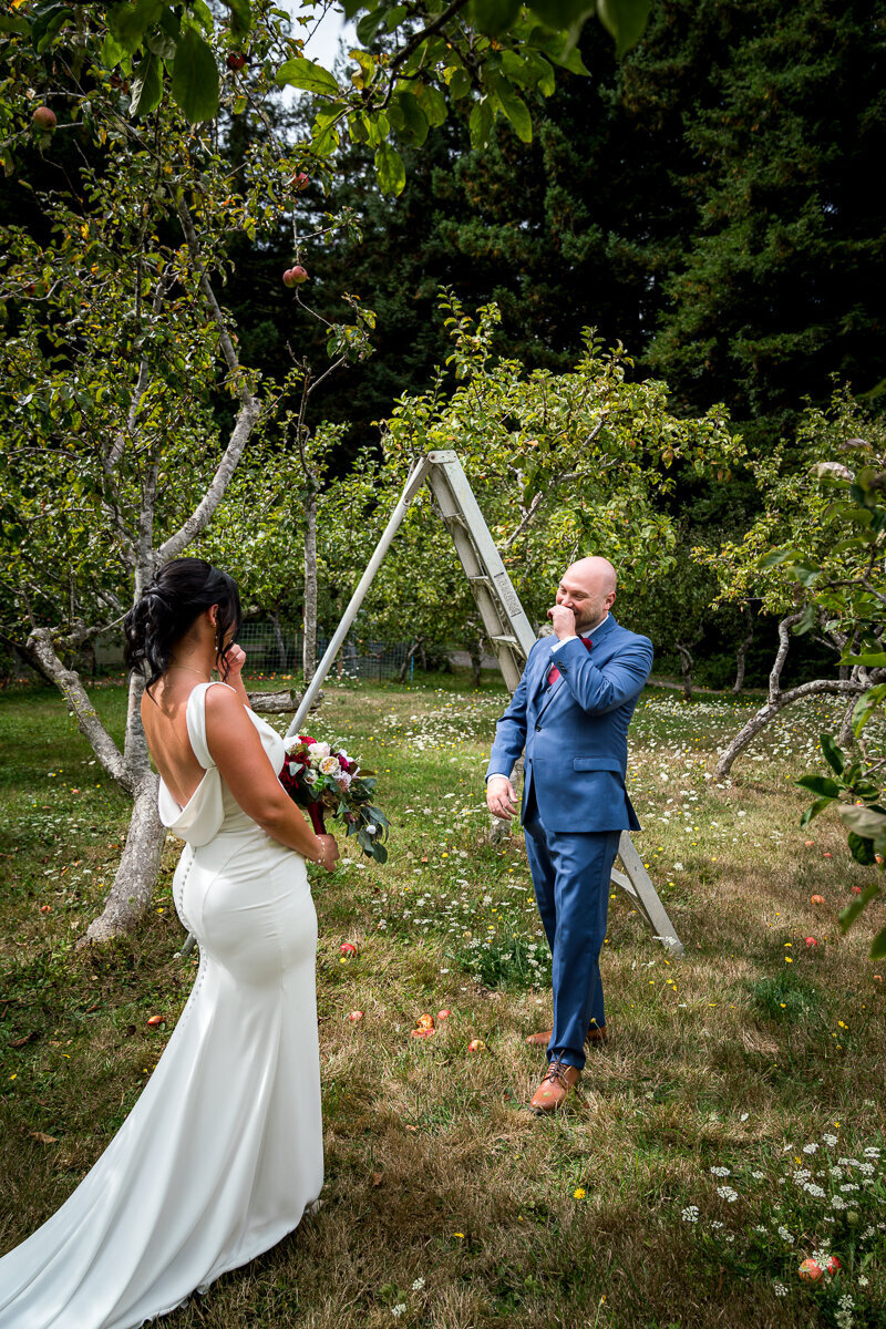 The groom’s face lights up with joy and awe as he sees his bride for the first time during their intimate first look in the serene orchard at Mitchell Grove in Eureka. A magical and heartfelt moment captured forever.