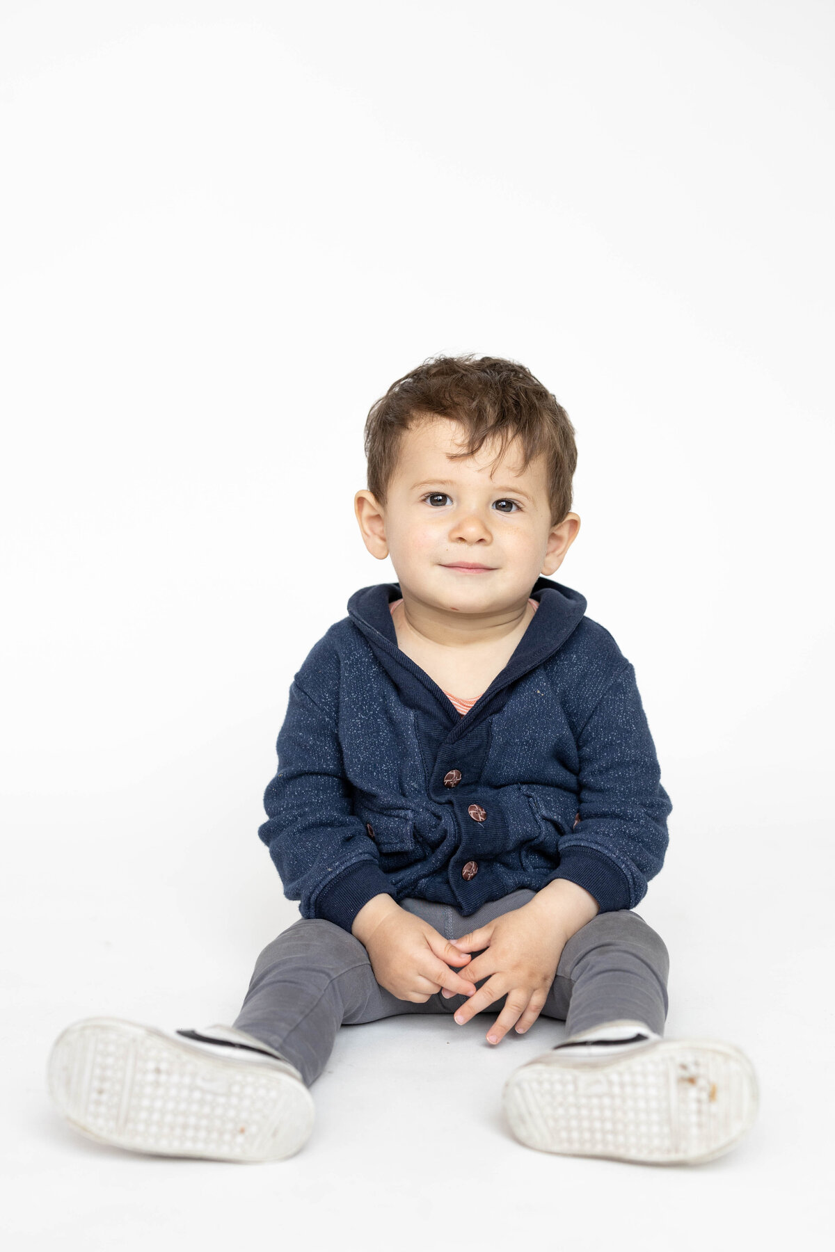 One year old boy sitting in a modern white backdrop