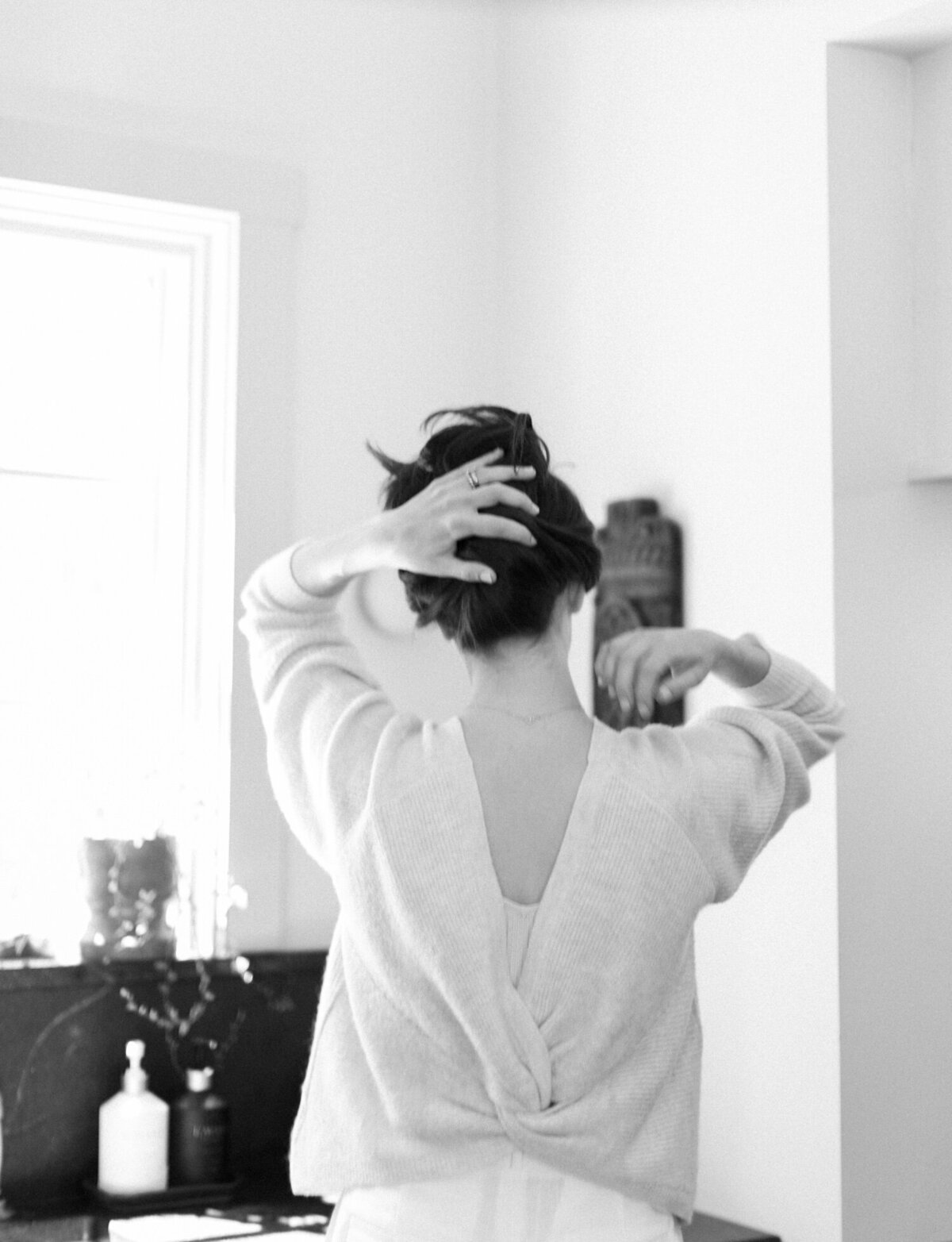 a designer holds up her hair from the back, lifestyle film branding photos for designer at Fernhaus, Michigan
