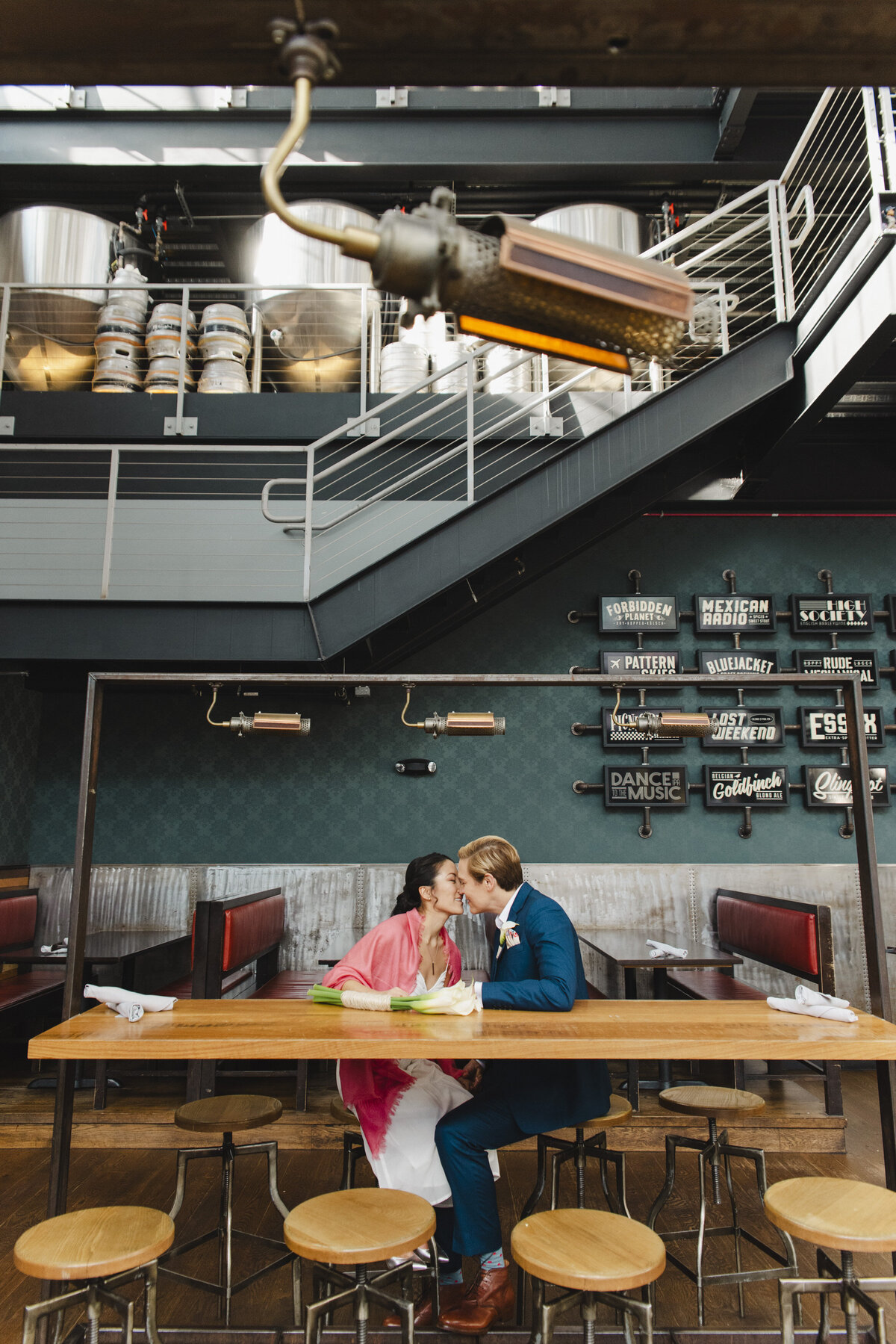 A newlywed couple sitting at a table kissing 