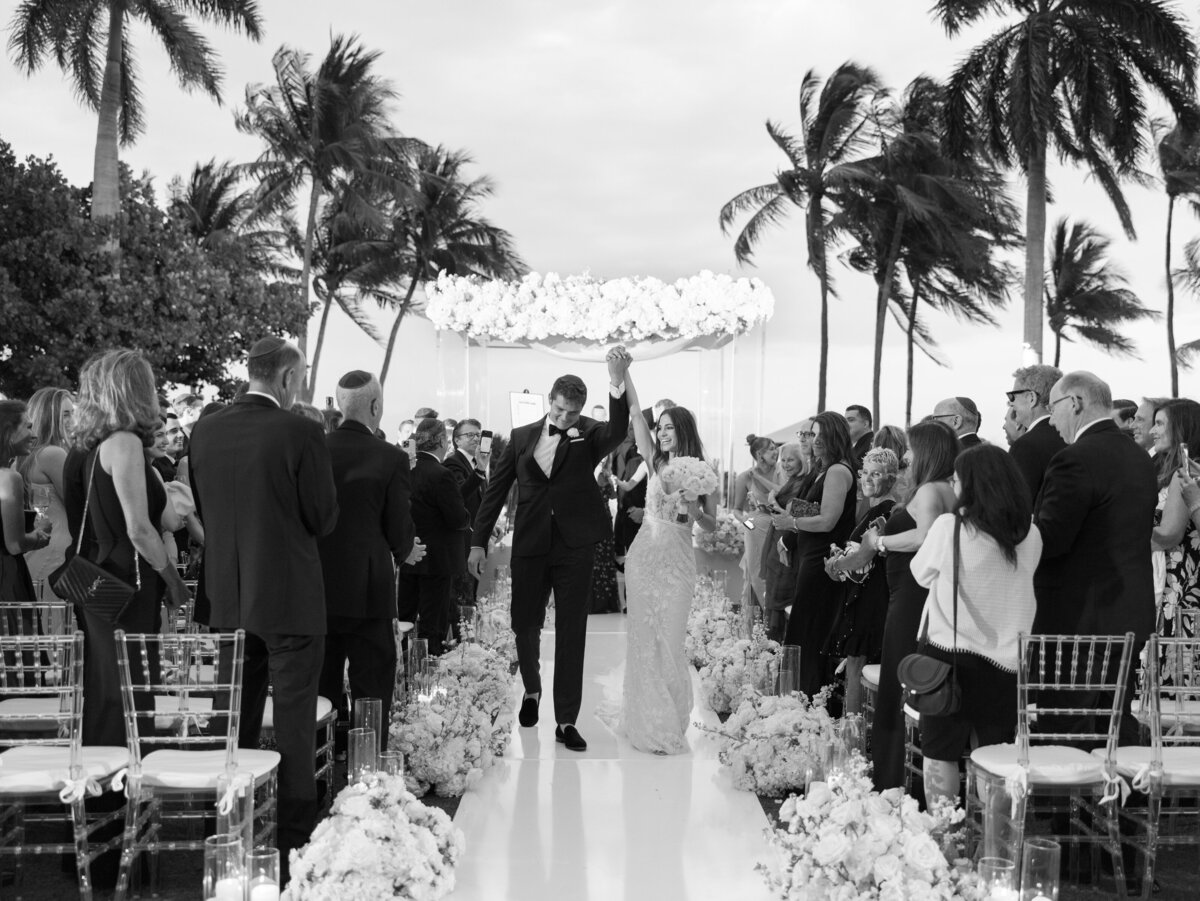 a bride and groom cheer as they walk down the aisle after becoming a married couple