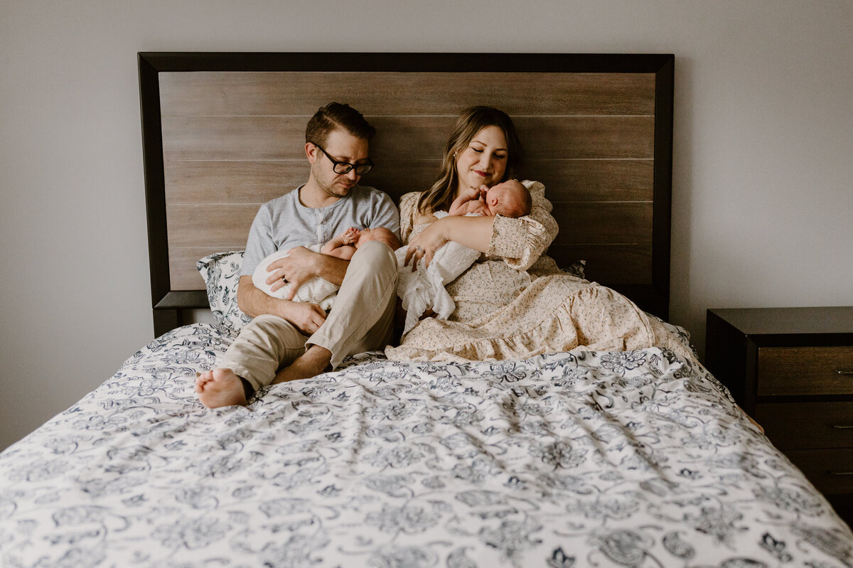 Parents sitting in bed newborn twins