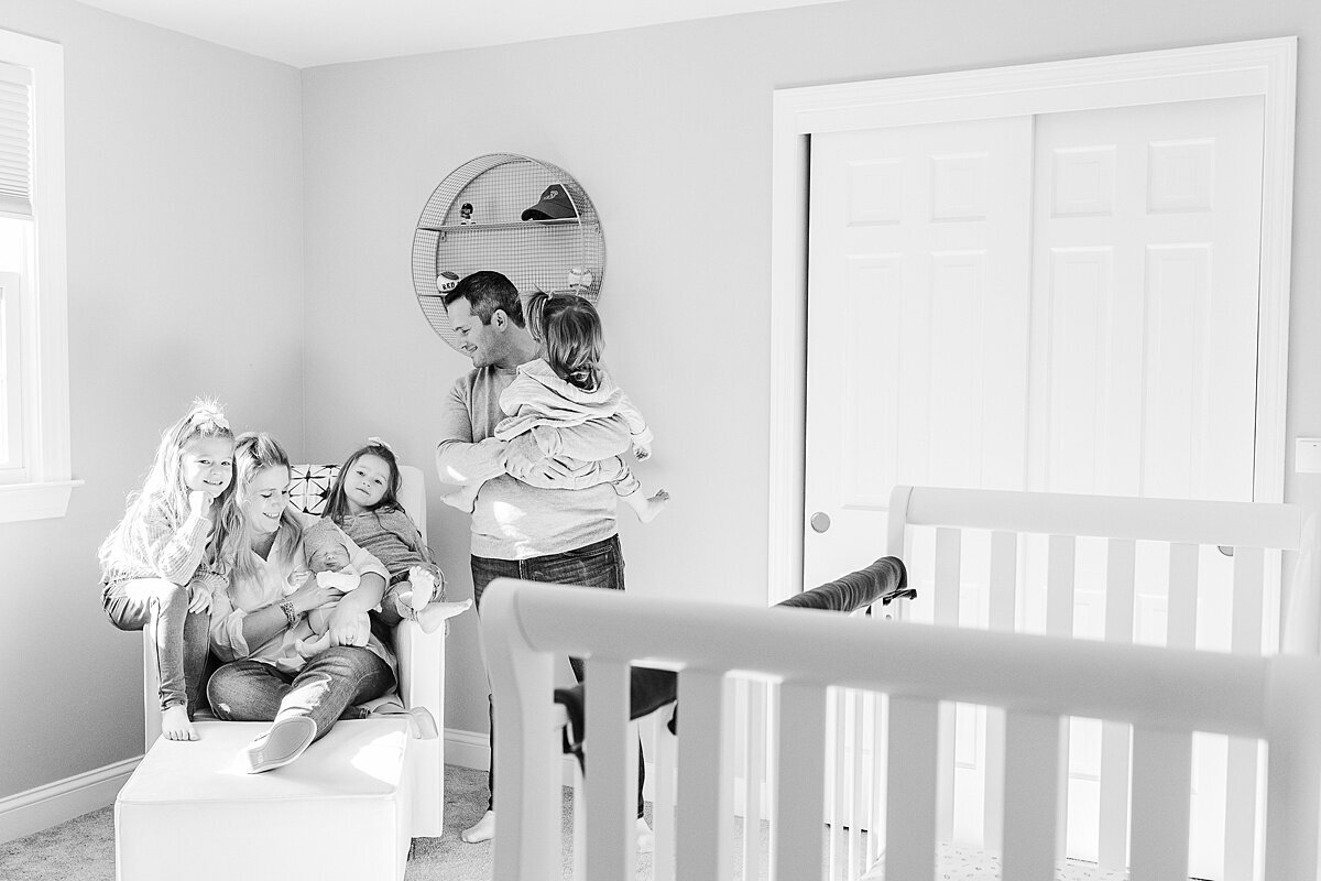family sits in nursery  during in home newborn photo session with Sara Sniderman Photography in Sherborn Massachusetts