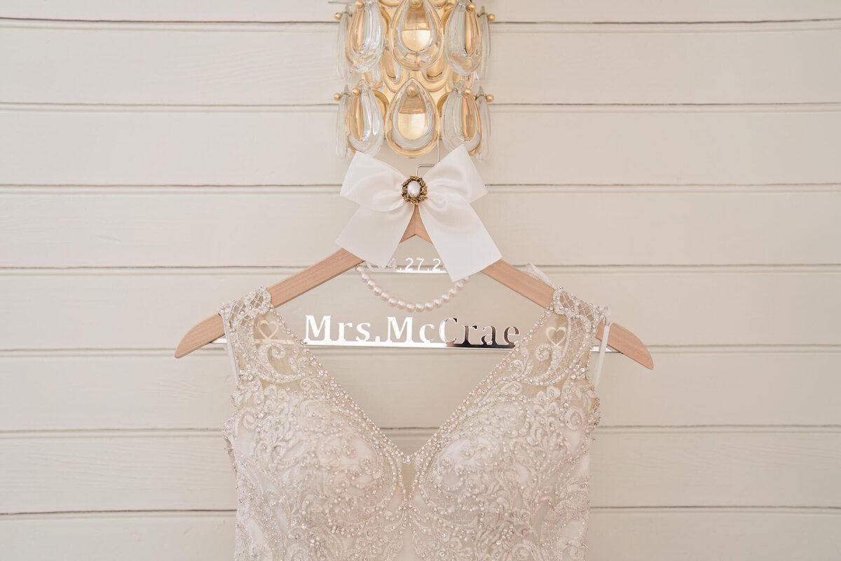 Beautiful lace wedding gown displayed on a personalized hanger, ready for the big day.