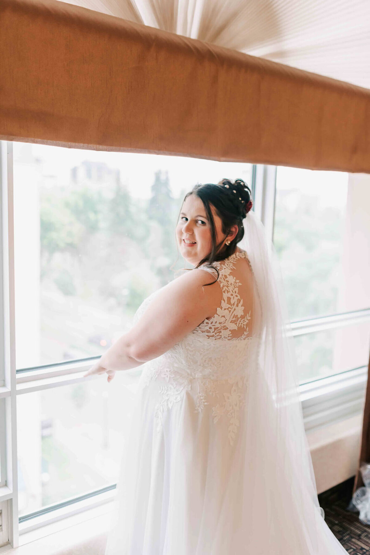 Bride ready to go, standing in front of the window.