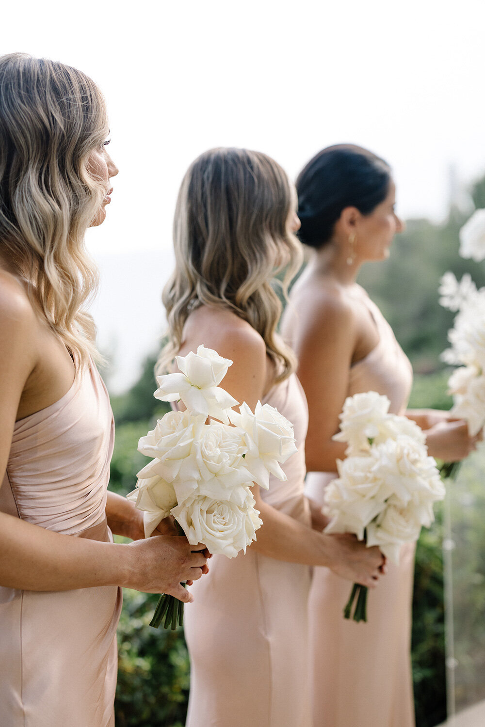 bridesmaids with soft pink dresses and minimalist all white rose bouquets