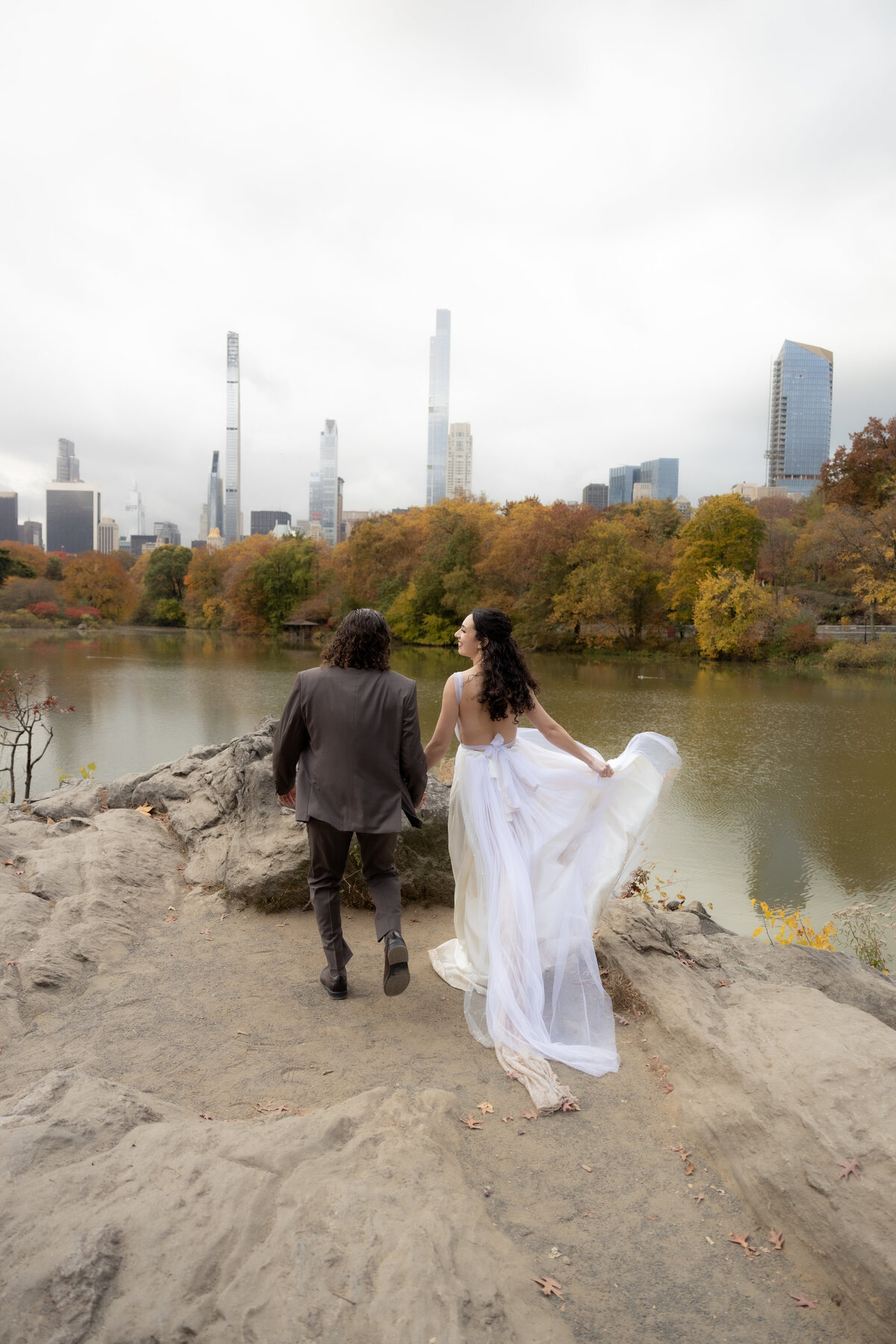 The couple standing close together surrounded by Central Park’s glowing fall foliage.