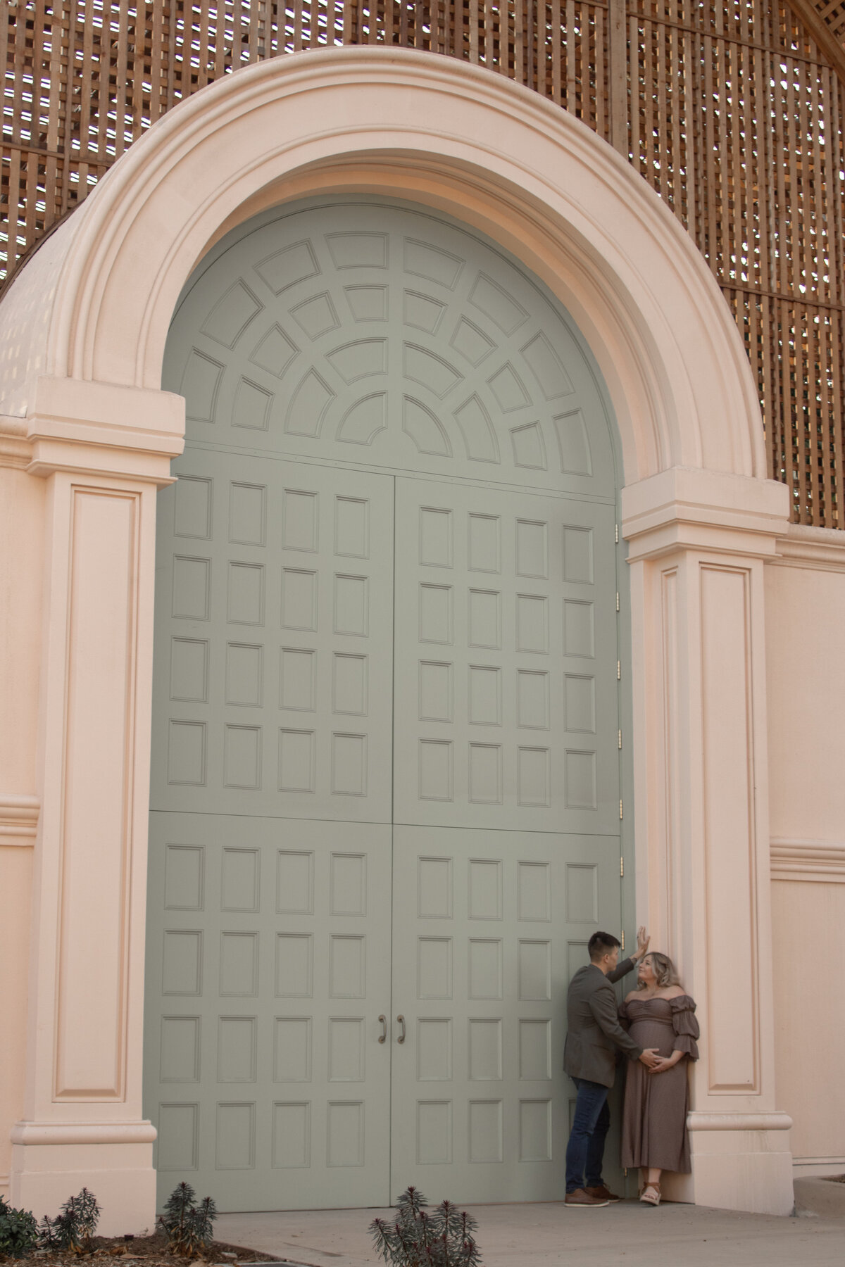 expecting mom and dad having an intimate moment in front of the botanical building in balboa park