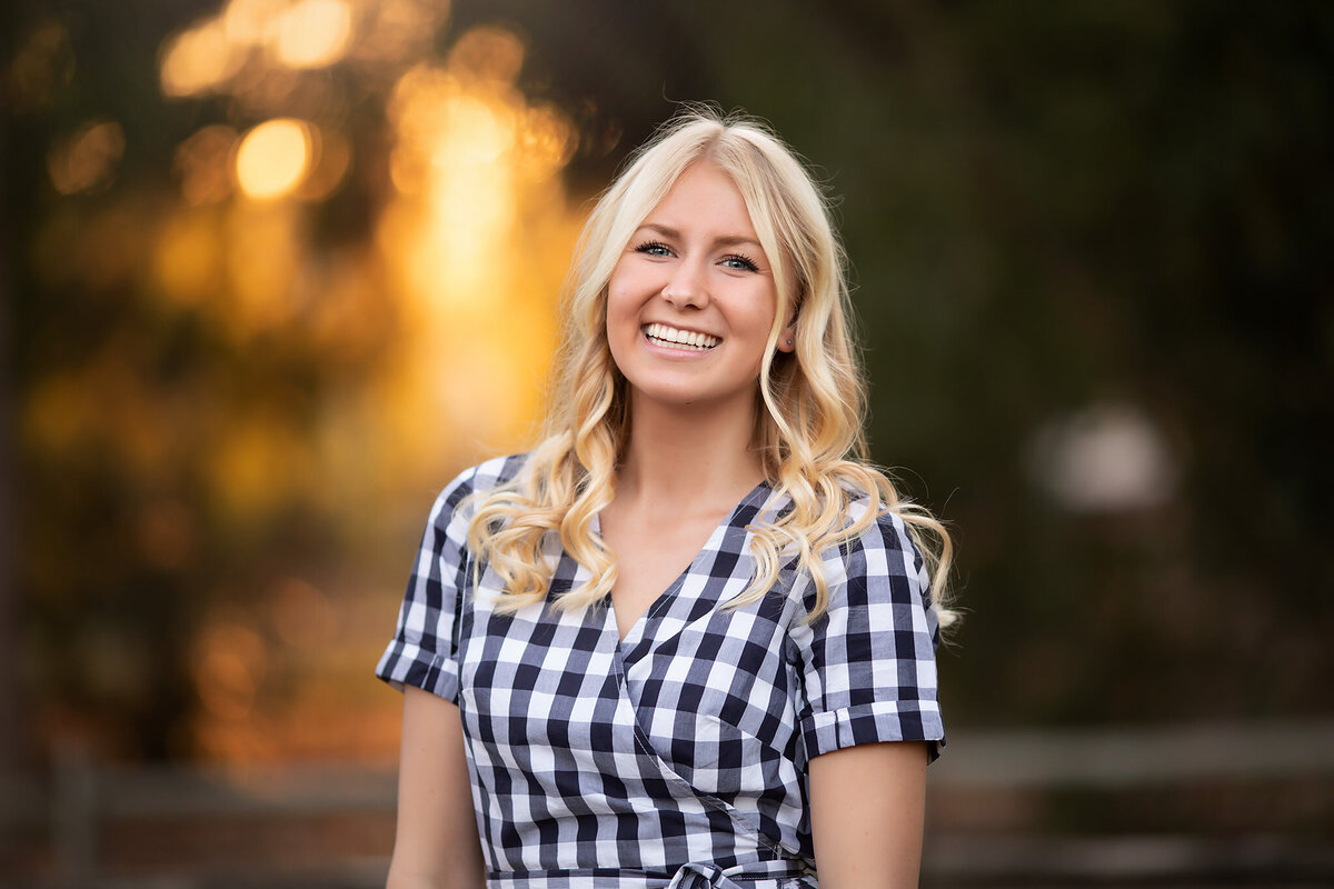 A young woman smiles warmly, captured in a family photo by a Dallas family photographer with a sunlit background.