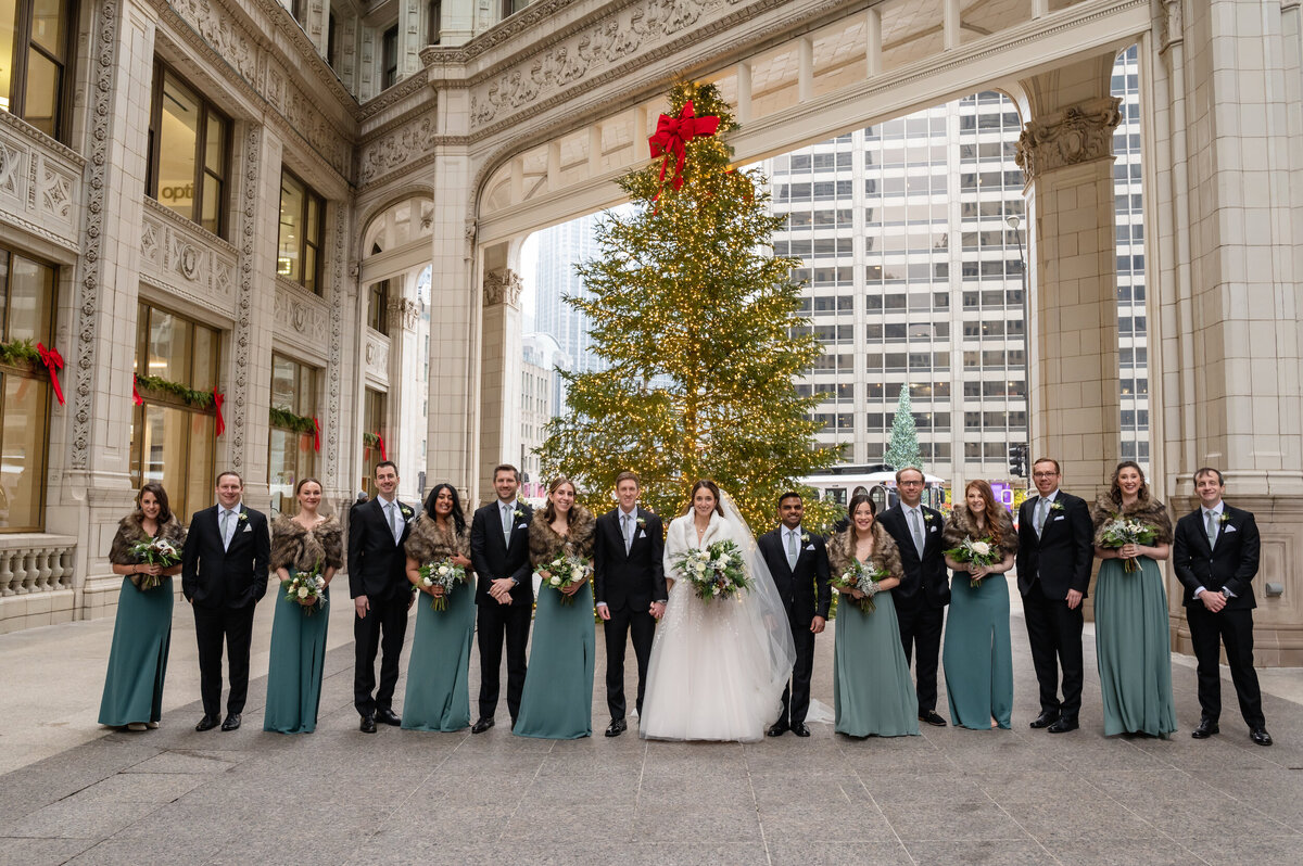 A wedding party walks with the bride and groom  at the Wrigley Building in Chicago