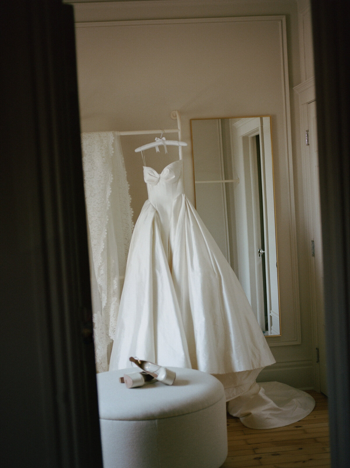 a raw silk Leah Dagloria wedding dress hangs in morning light, documented by film wedding photographer Christina Harrison